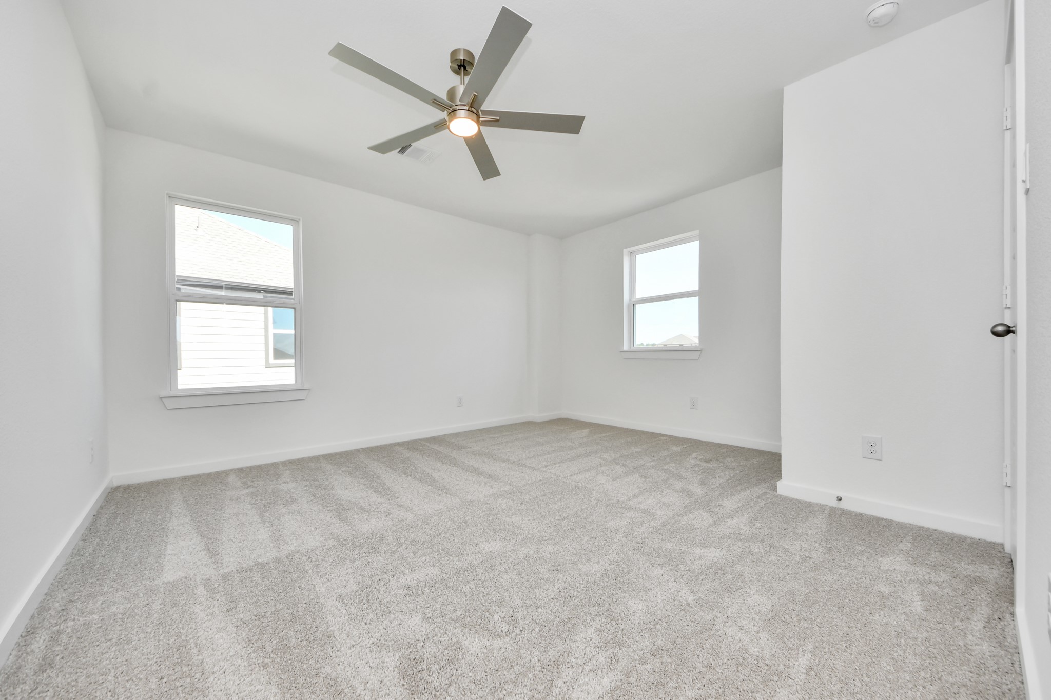 Secondary bedroom features plush carpeting, large windows that let in plenty of natural light, bright paint, and spacious closets.