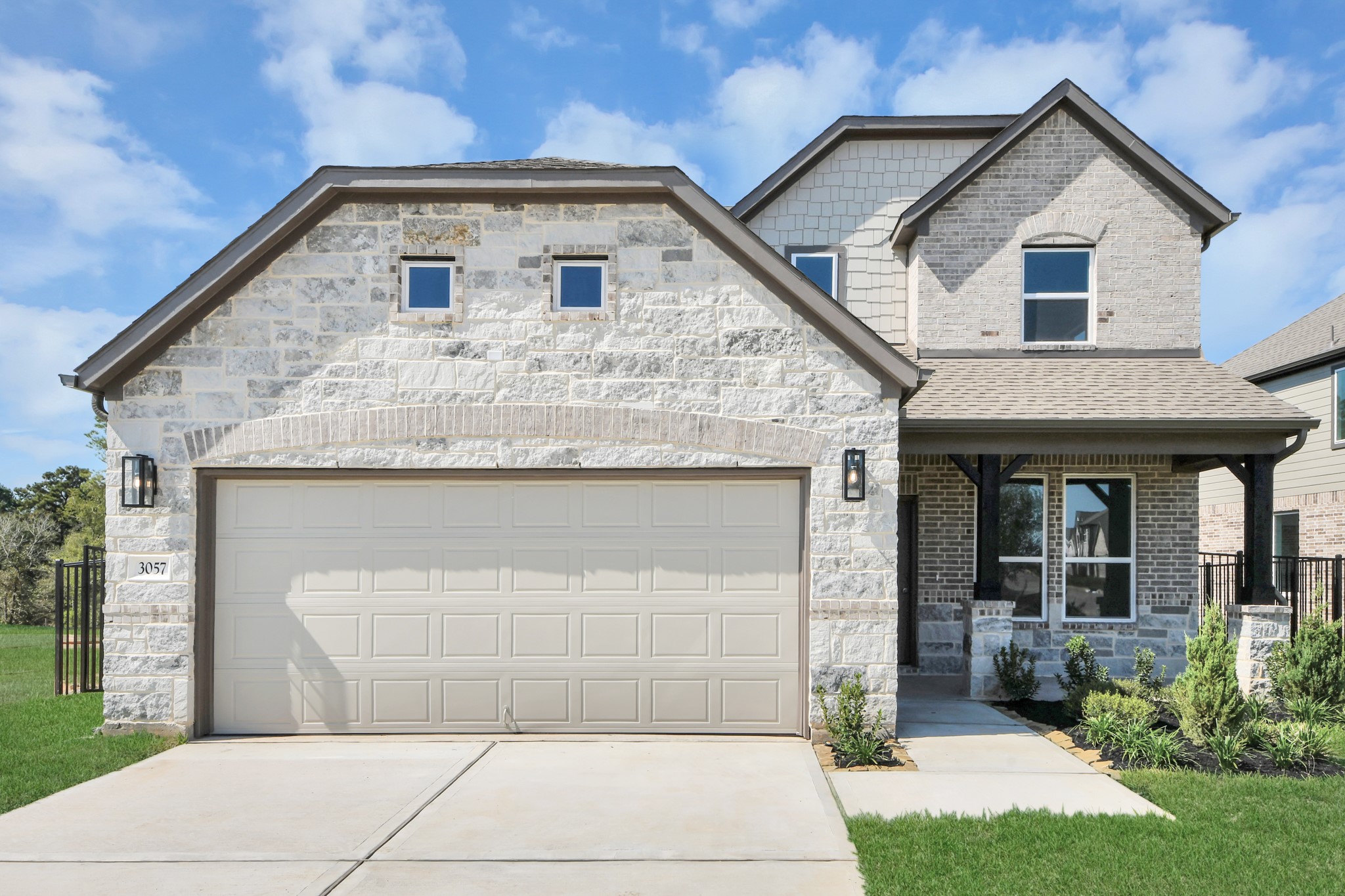 Meticulously maintained yard and lush landscape, paired with a premium elevation featuring captivating brick accents. Modern coach lights add a touch of contemporary elegance to the exterior.