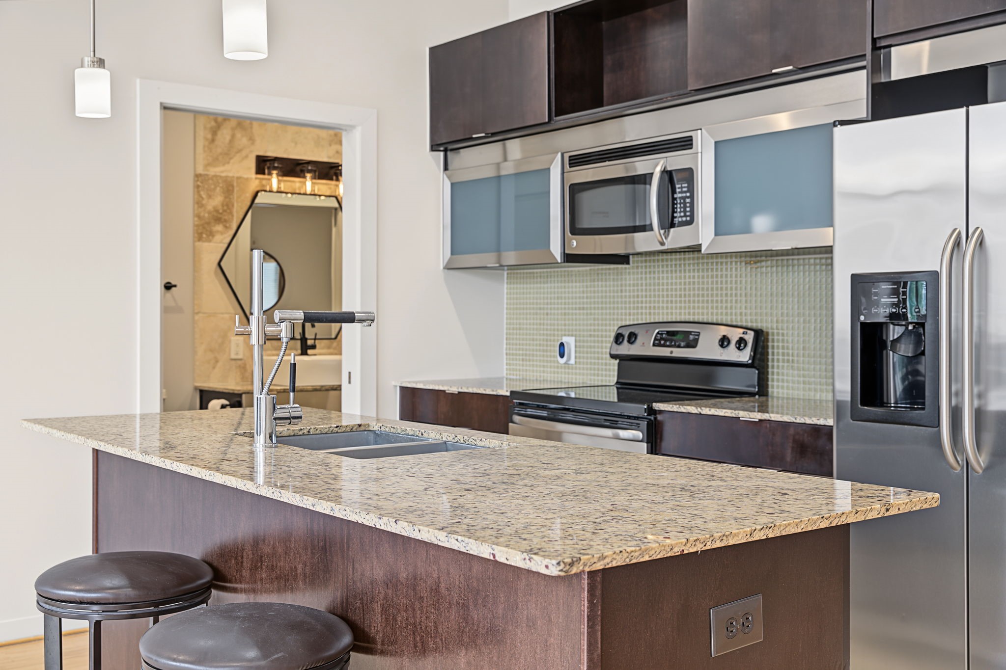 Modern European-style cabinetry with frosted glass-front shelving brings a sophisticated, contemporary flair to the kitchen while blending style with everyday functionality. Beautiful granite countertops, recessed lighting, and sparkling stainless steel appliances complete this stylish, modern space!