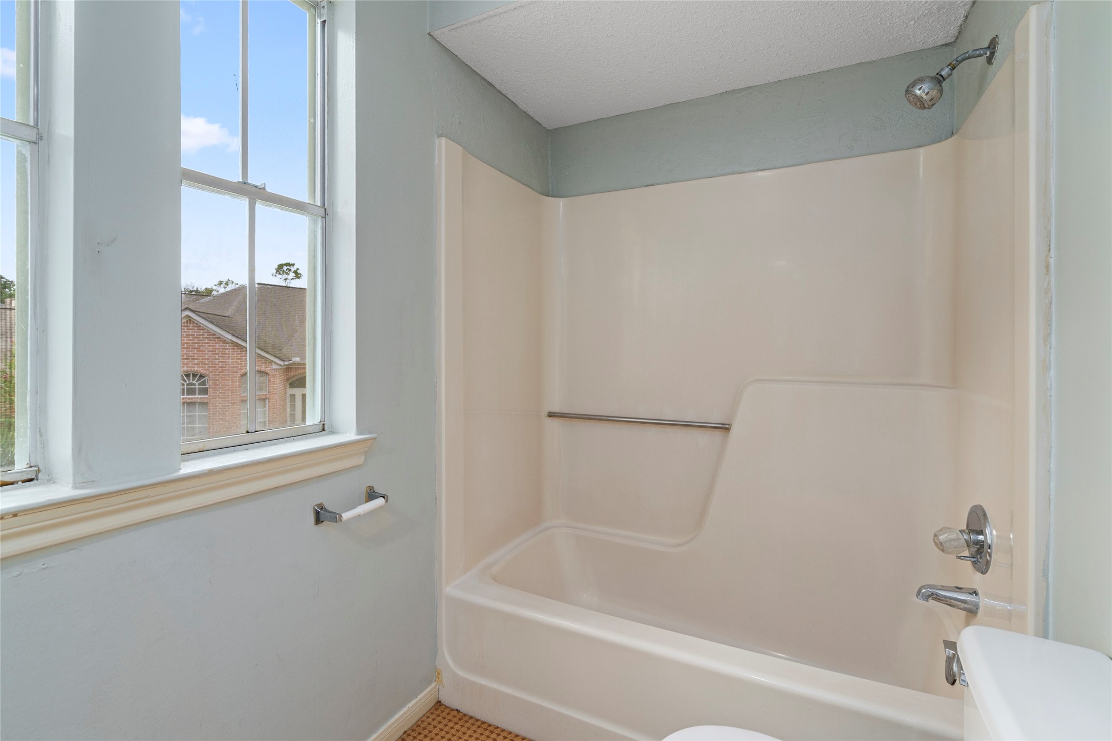 Secondary bathroom with tub and shower combination, practical and ready for a refresh to suit personal style.