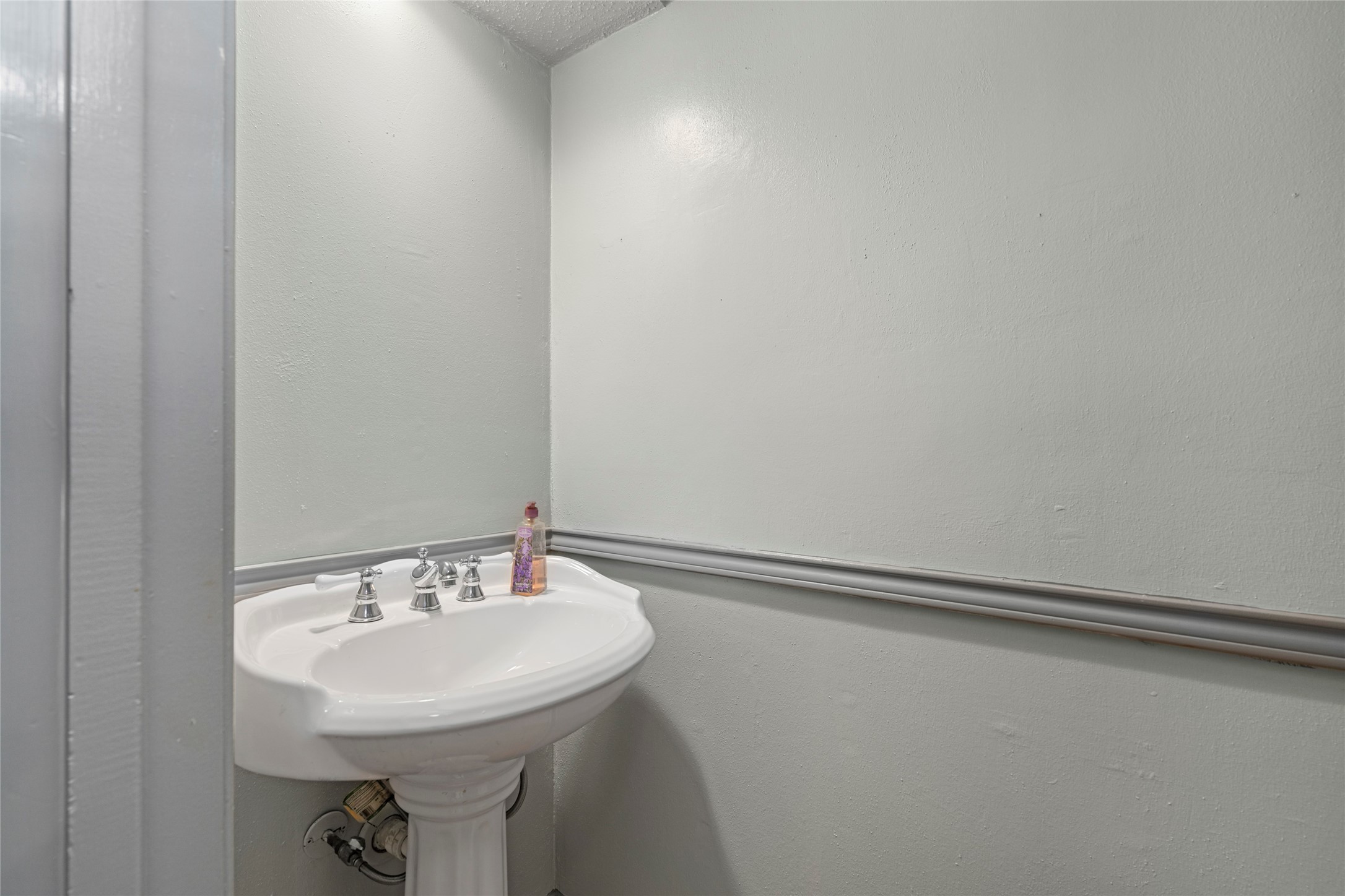 A convenient powder room with a classic pedestal sink, ideal for guests.