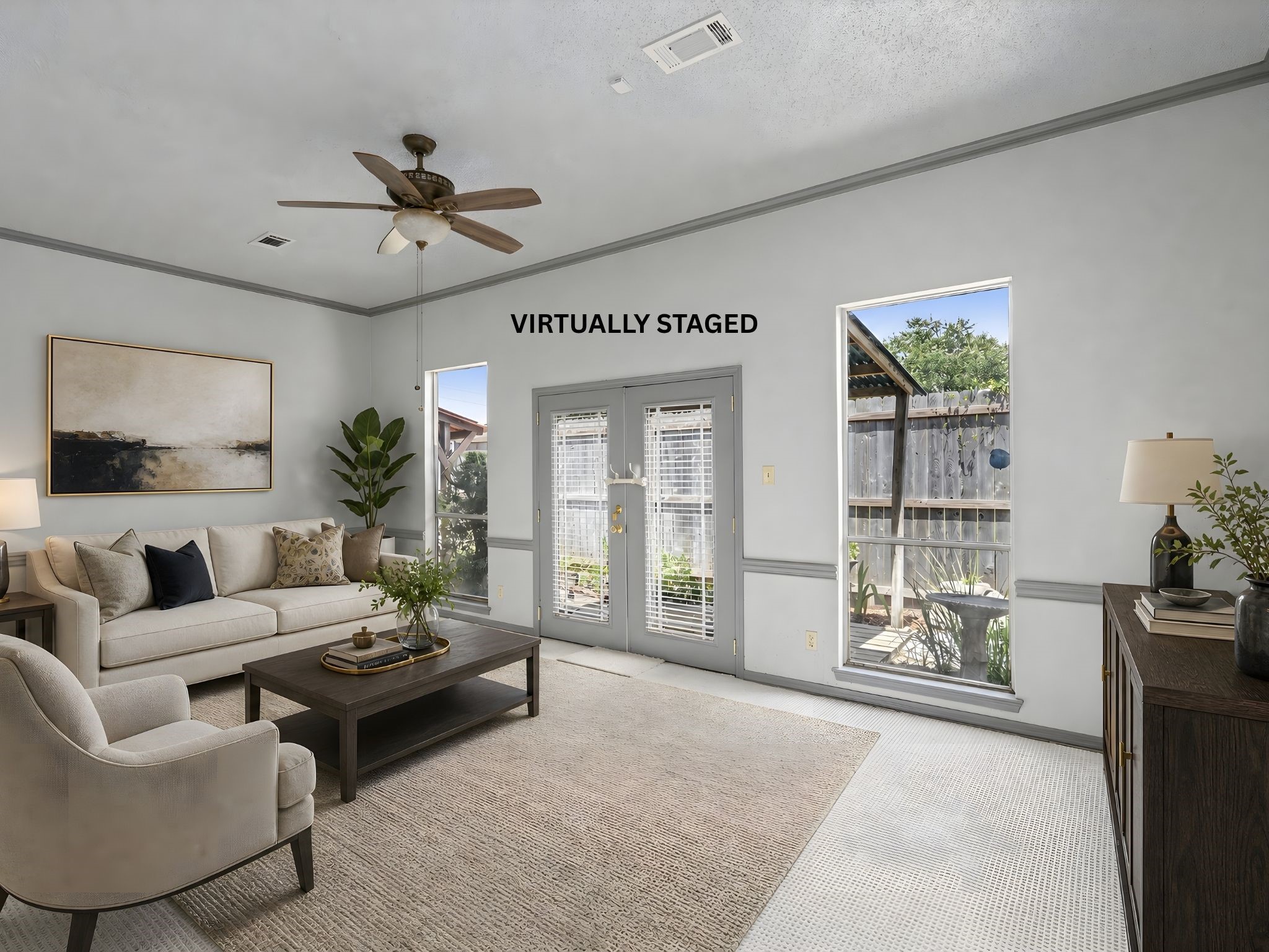 A virtually staged living room view with French doors, showing how natural light and a comfortable seating arrangement make this an inviting retreat.