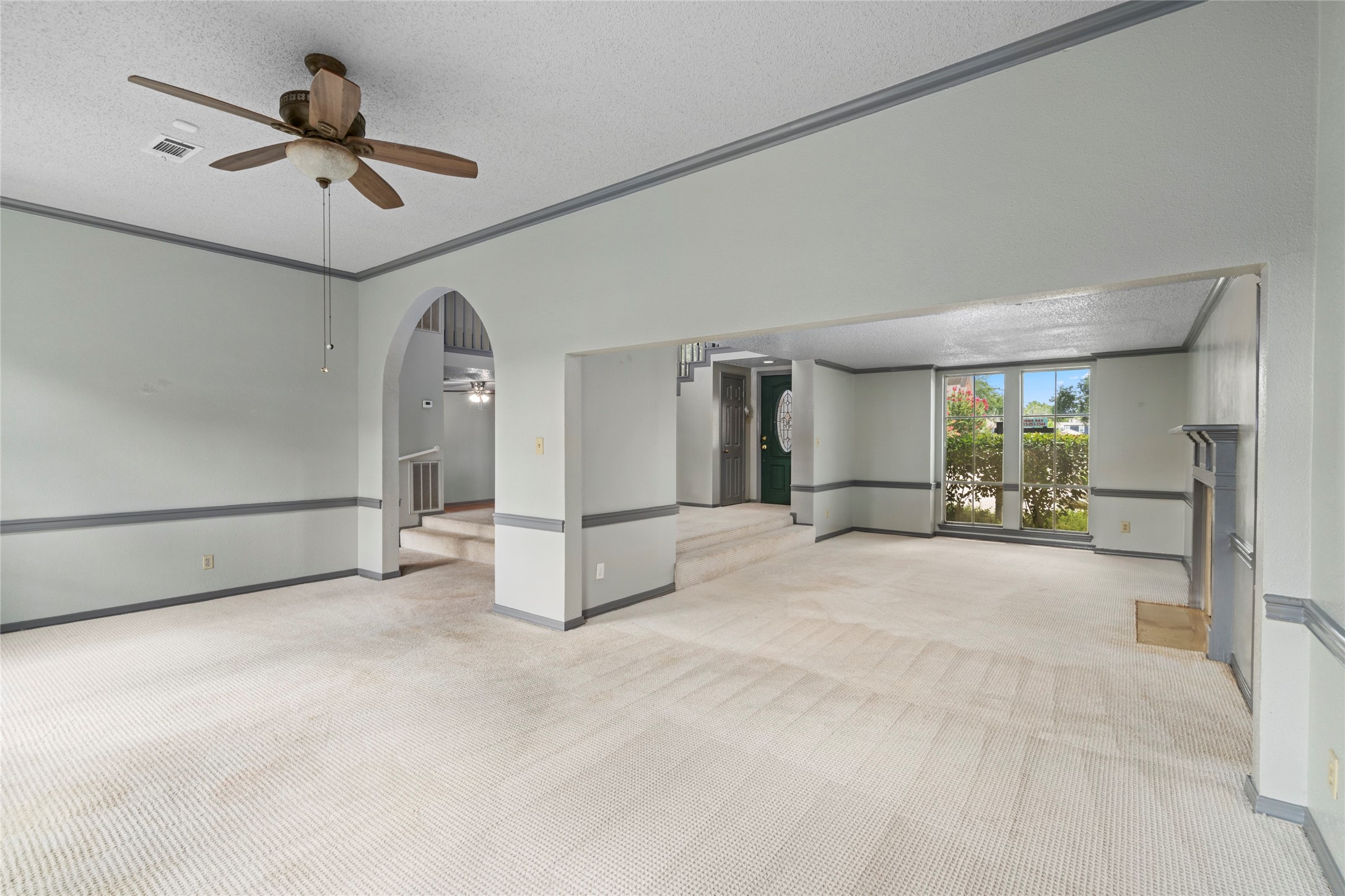 A wide-angle virtually staged view of the living room, emphasizing the airy, open-concept feel created by the arched doorways.