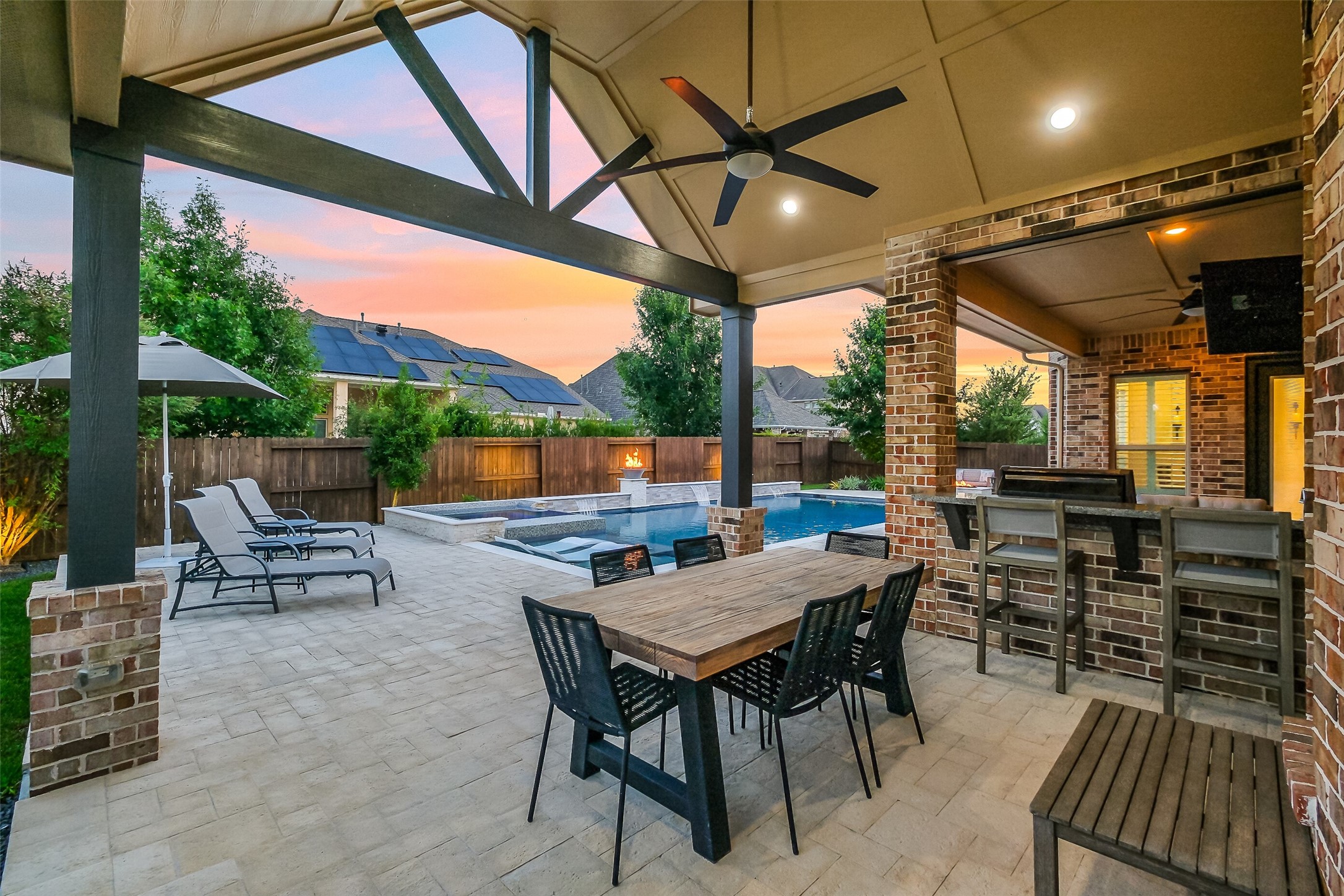 As the sun sets, this extended covered outdoor dining and kitchen area truly comes alive complete with a ceiling fan, surround sound, outdoor grill, and bar seating overlooking the pool. It's an entertainer's go-to spot for Texas evenings. As the sun sets, this extended covered outdoor dining and kitchen area truly comes alive complete with a ceiling fan, surround sound, outdoor grill, and bar seating overlooking the pool. It's an entertainer's go-to spot for Texas evenings.
