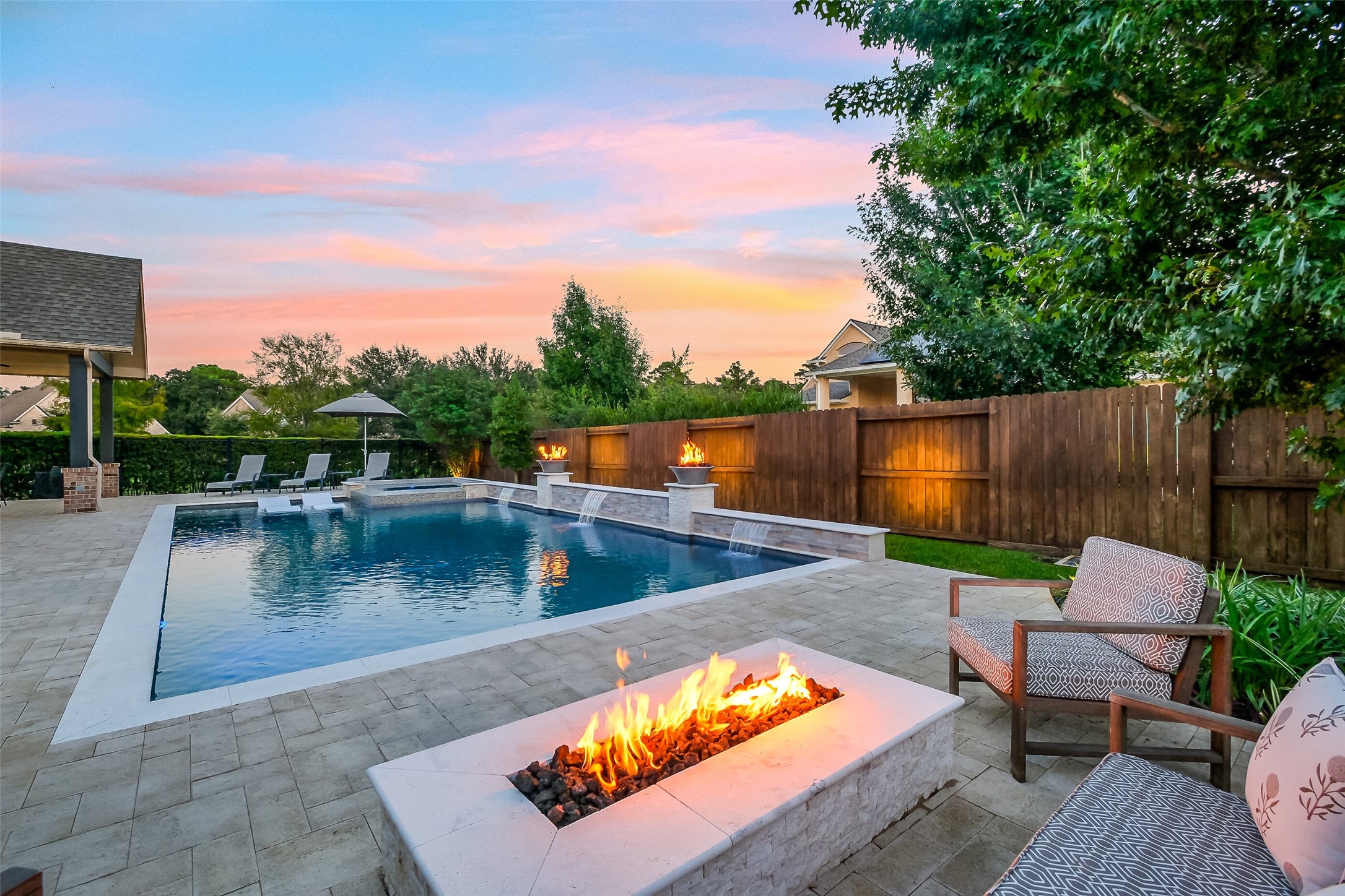 When the weather cools, youll appreciate the built-in linear firepit overlooking the pool and spa. The fire bowls, water features, and landscape lighting add to the ambiance for relaxed evenings in this backyard retreat. When the weather cools, youll appreciate the built-in linear firepit overlooking the pool and spa. The fire bowls, water features, and landscape lighting add to the ambiance for relaxed evenings in this backyard retreat.