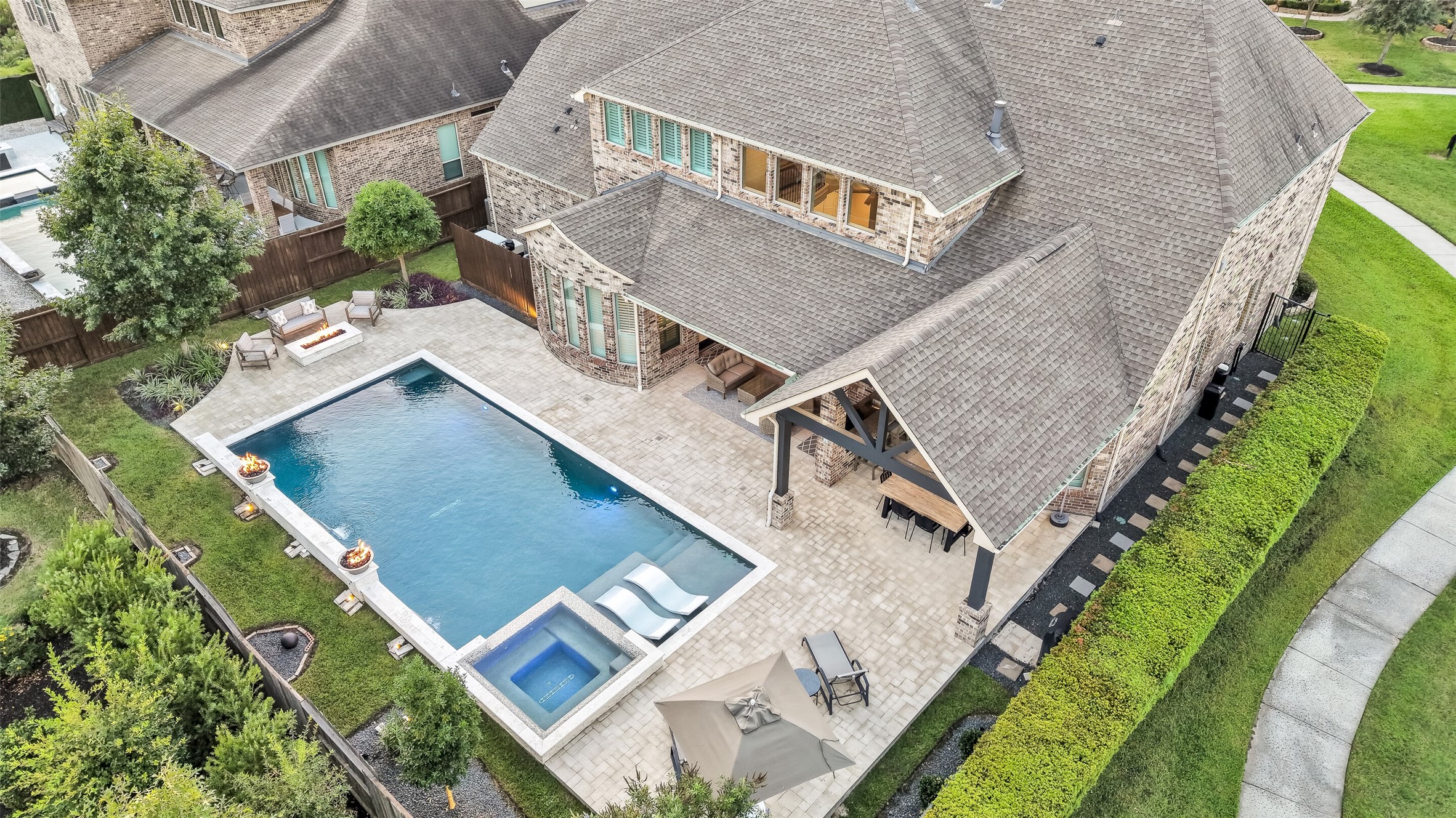 This aerial view captures the full scope of the private backyard retreat: a custom heated pool and raised spa, a spacious paver patio, built-in fire bowls, fire pit area and covered outdoor living and dining areas all ready for effortless indoor-outdoor entertaining. This aerial view captures the full scope of the private backyard retreat: a custom heated pool and raised spa, a spacious paver patio, built-in fire bowls, fire pit area and covered outdoor living and dining areas all ready for effortless indoor-outdoor entertaining.