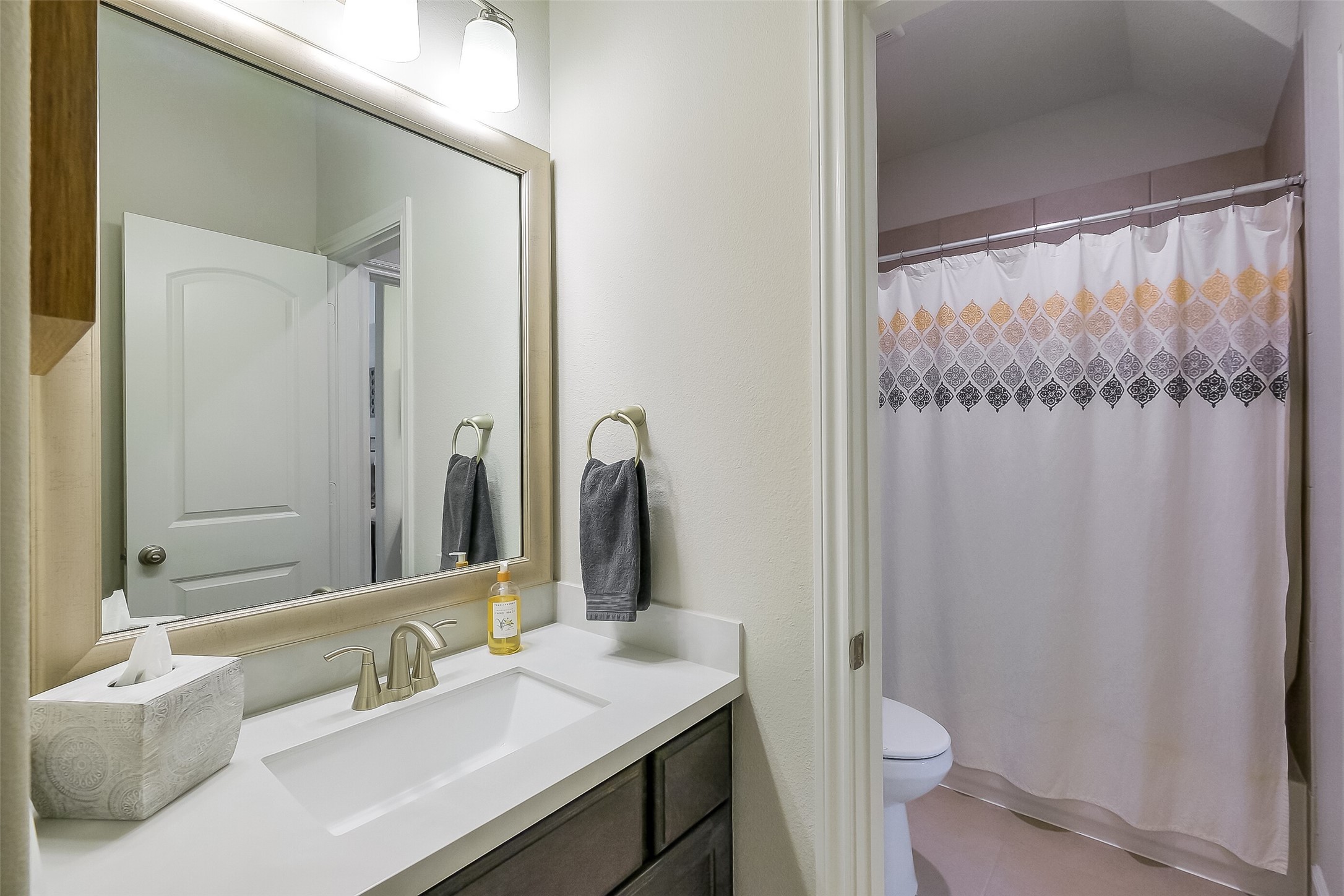 This secondary first floor full bathroom offers a quartz-topped vanity, brushed nickel fixtures, and a tiled tub/shower  a clean, comfortable space for guests or family.