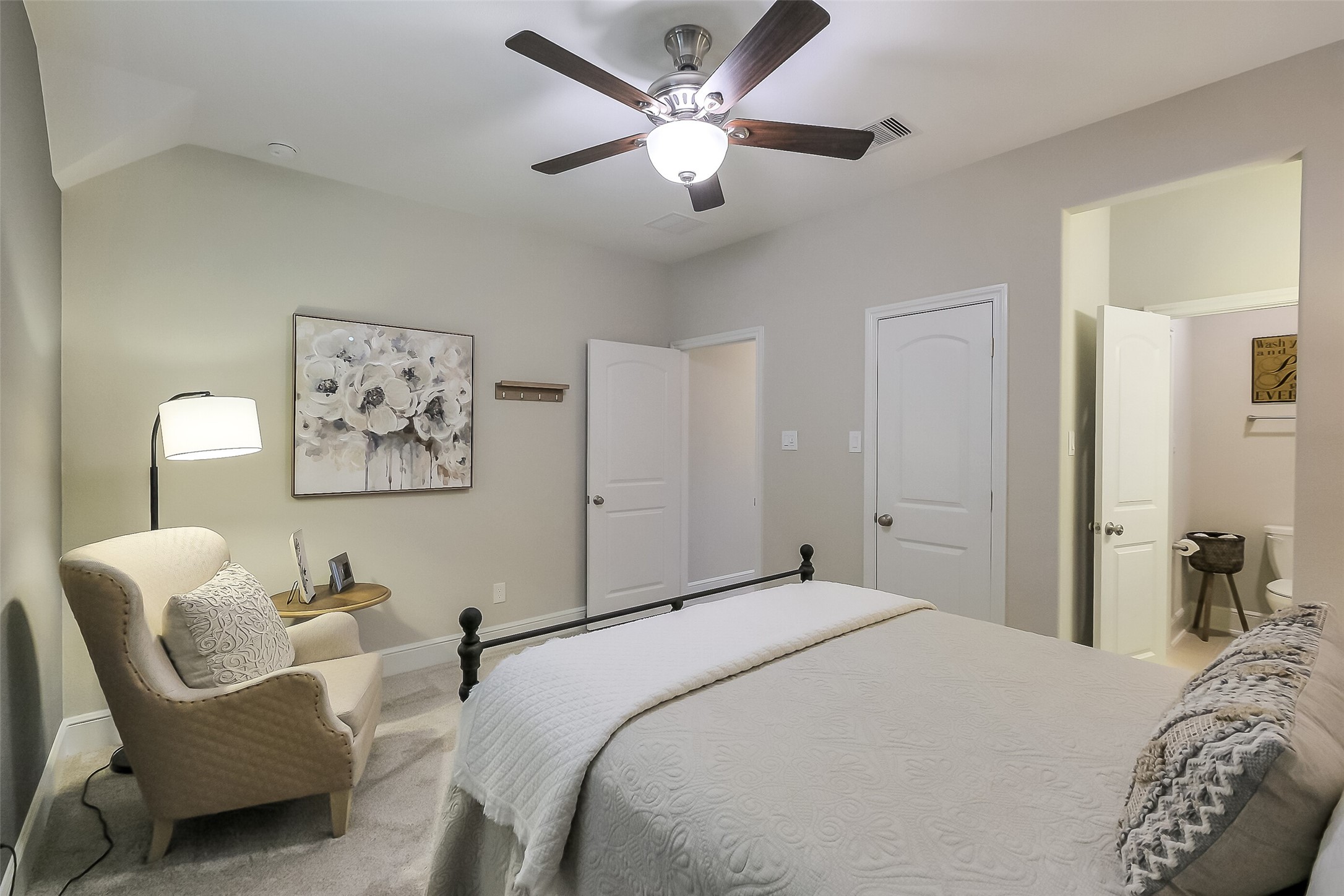 This upstairs bedroom offers comfort and convenience with a ceiling fan, neutral carpet, and an en-suite bathroom just steps away.