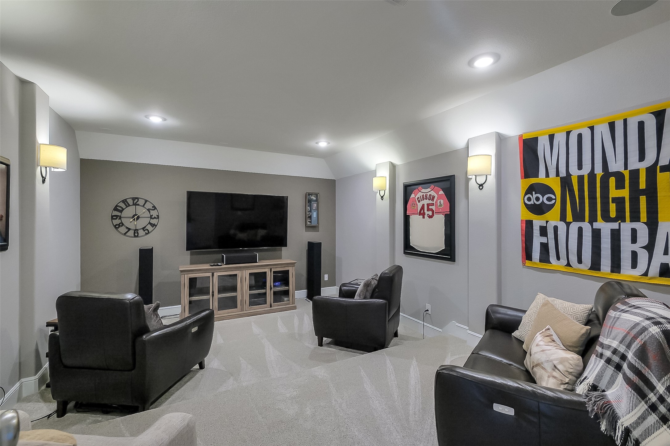 This media or game room is ready for movie marathons or big-game watch parties, with stadium seating with plush carpet, soft sconce lighting, and wired for surround sound.