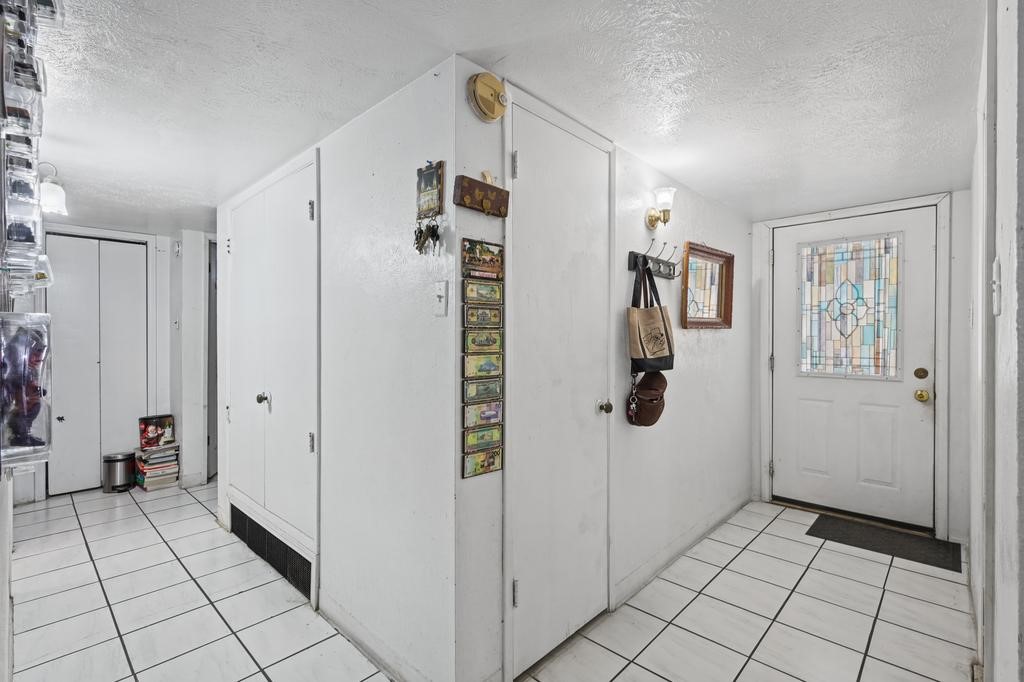 Bright entryway featuring a stained glass door, tiled floor, and ample storage with closets and hooks for convenience.