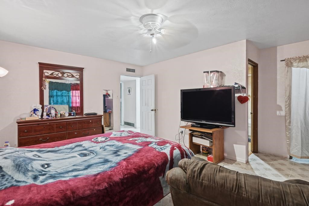 Cozy bedroom featuring a plush bed with unique bedding, a spacious dresser with mirror, and a mounted TV for entertainment.