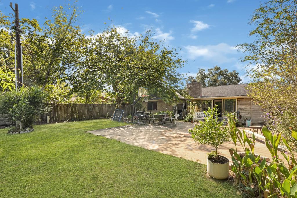 Spacious backyard retreat with lush greenery, a large patio for outdoor entertaining, and mature trees providing shade and privacy.