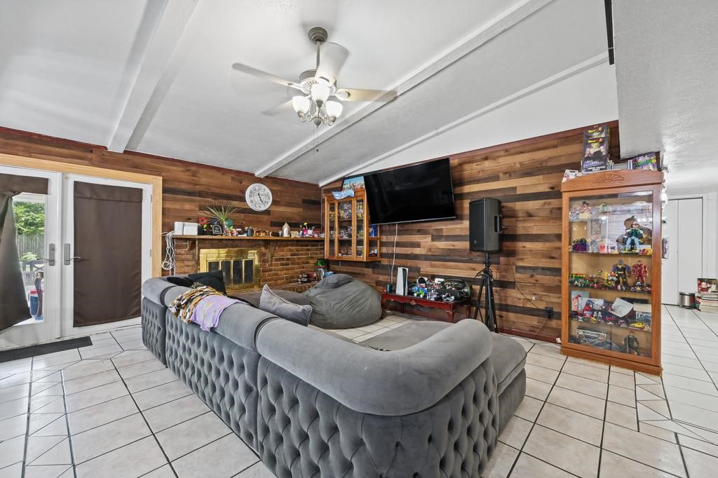 Spacious living room featuring a cozy fireplace, wood accent walls, and ample natural light from large glass doors.