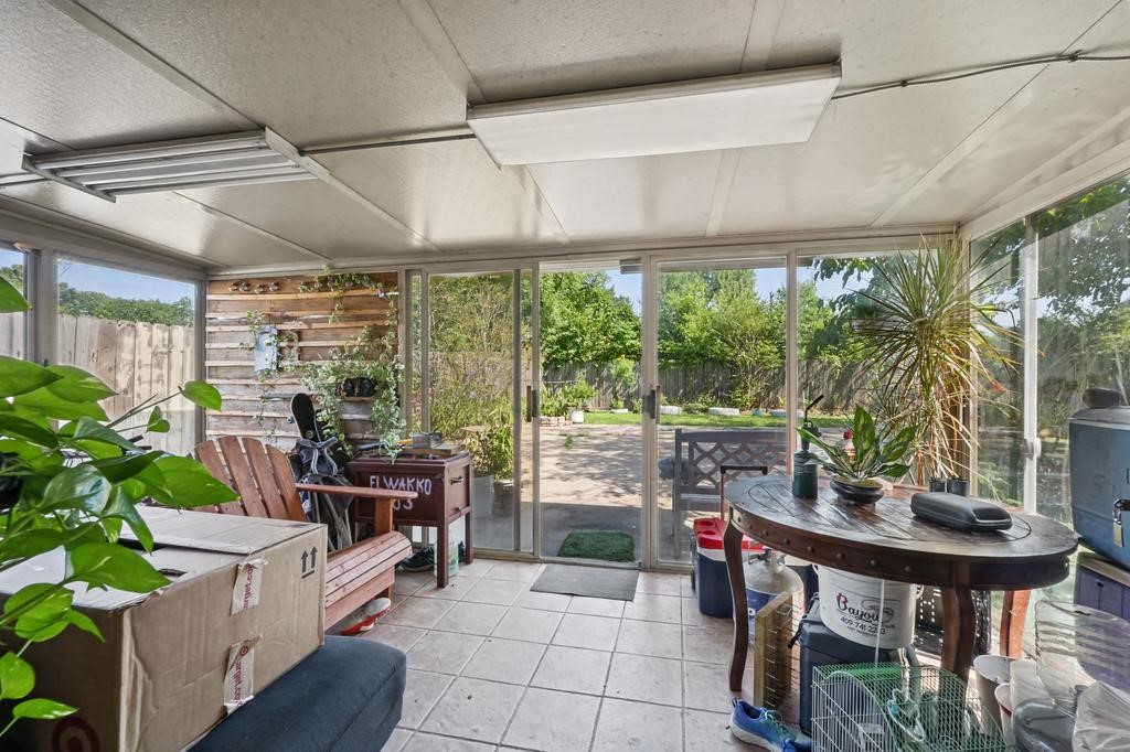 Sunroom with tiled floors and abundant natural light, perfect for relaxation and enjoying views of the lush backyard through large sliding glass doors.