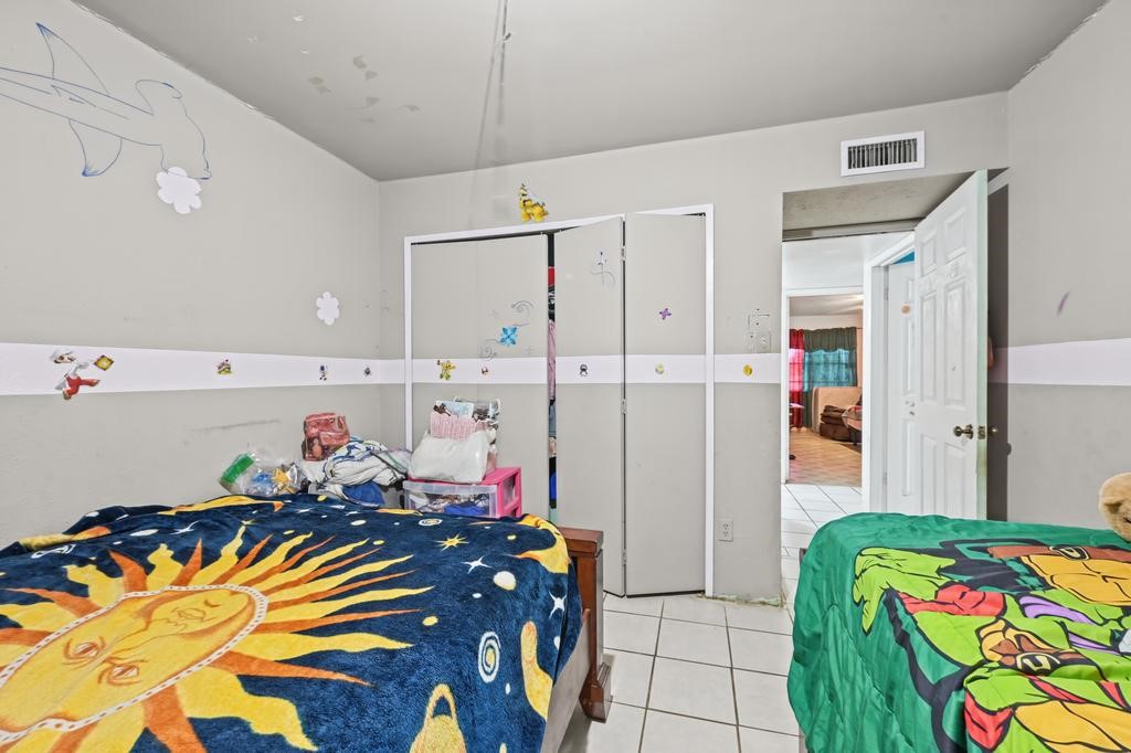 Charming children's bedroom with playful decor, featuring tiled flooring, creative wall accents, and ample closet space.
