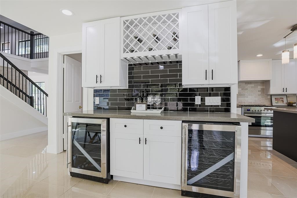 Stylish bar area featuring shaker-style cabinets and a striking black backsplash, offering a sleek contrast. The design blends timeless elegance with modern sophistication, creating the perfect space for entertaining.