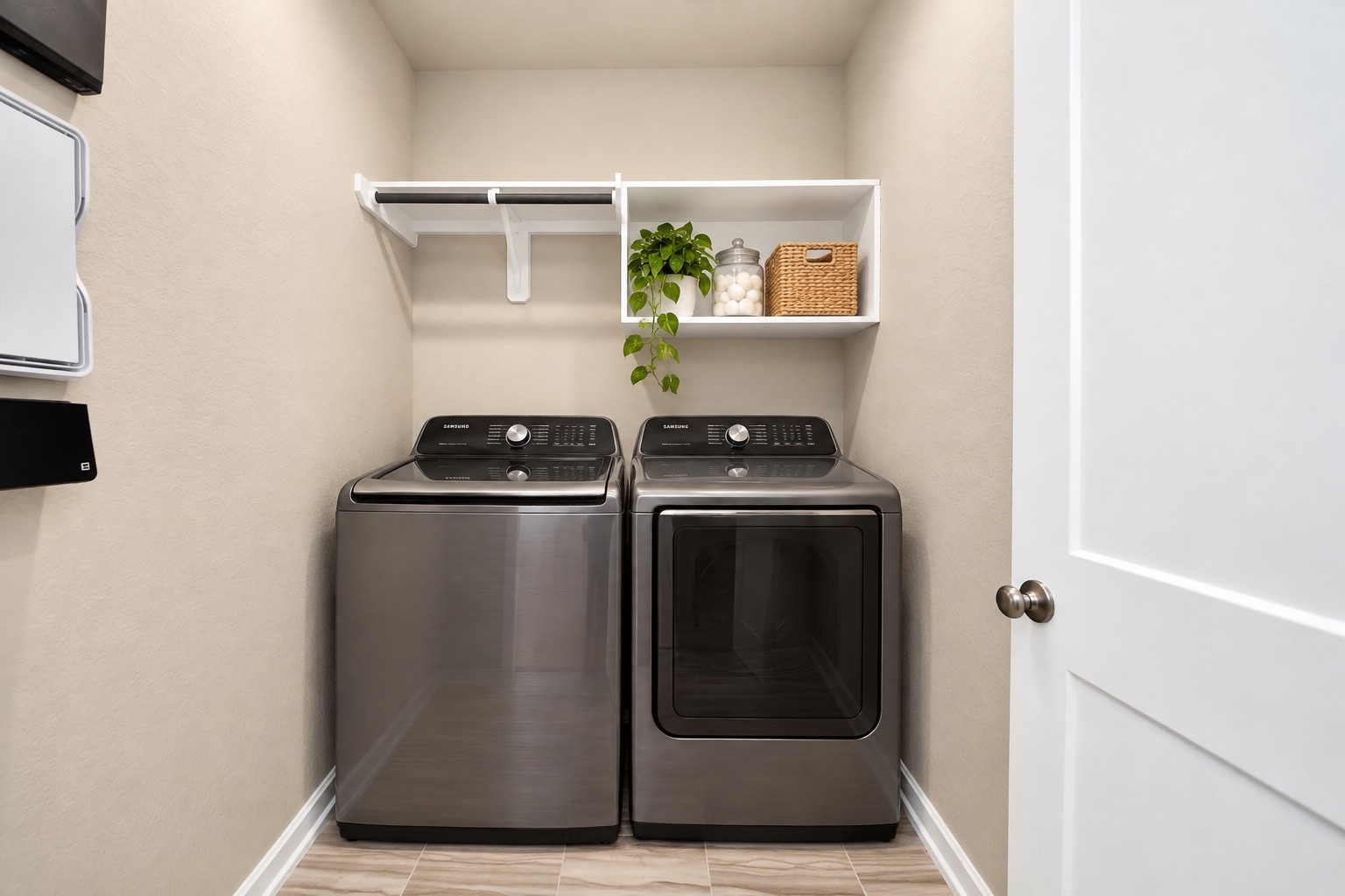 Convenient indoor utility room with built-in shelving and space for full sized laundry appliances.