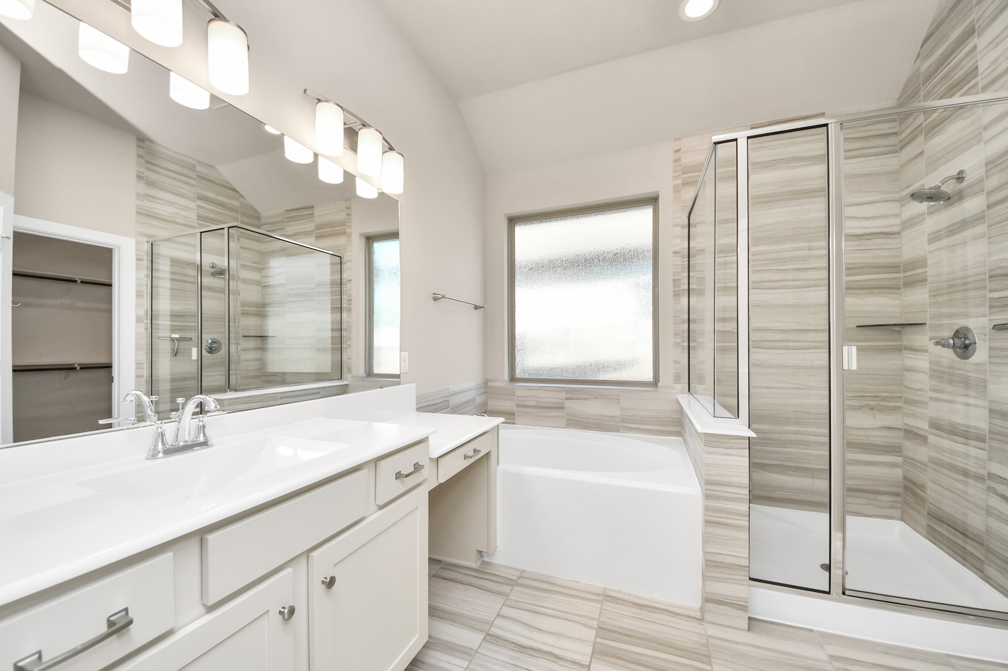 Luxurious primary bathroom featuring dual vanities, a soaking tub, and a separate glass enclosed shower.