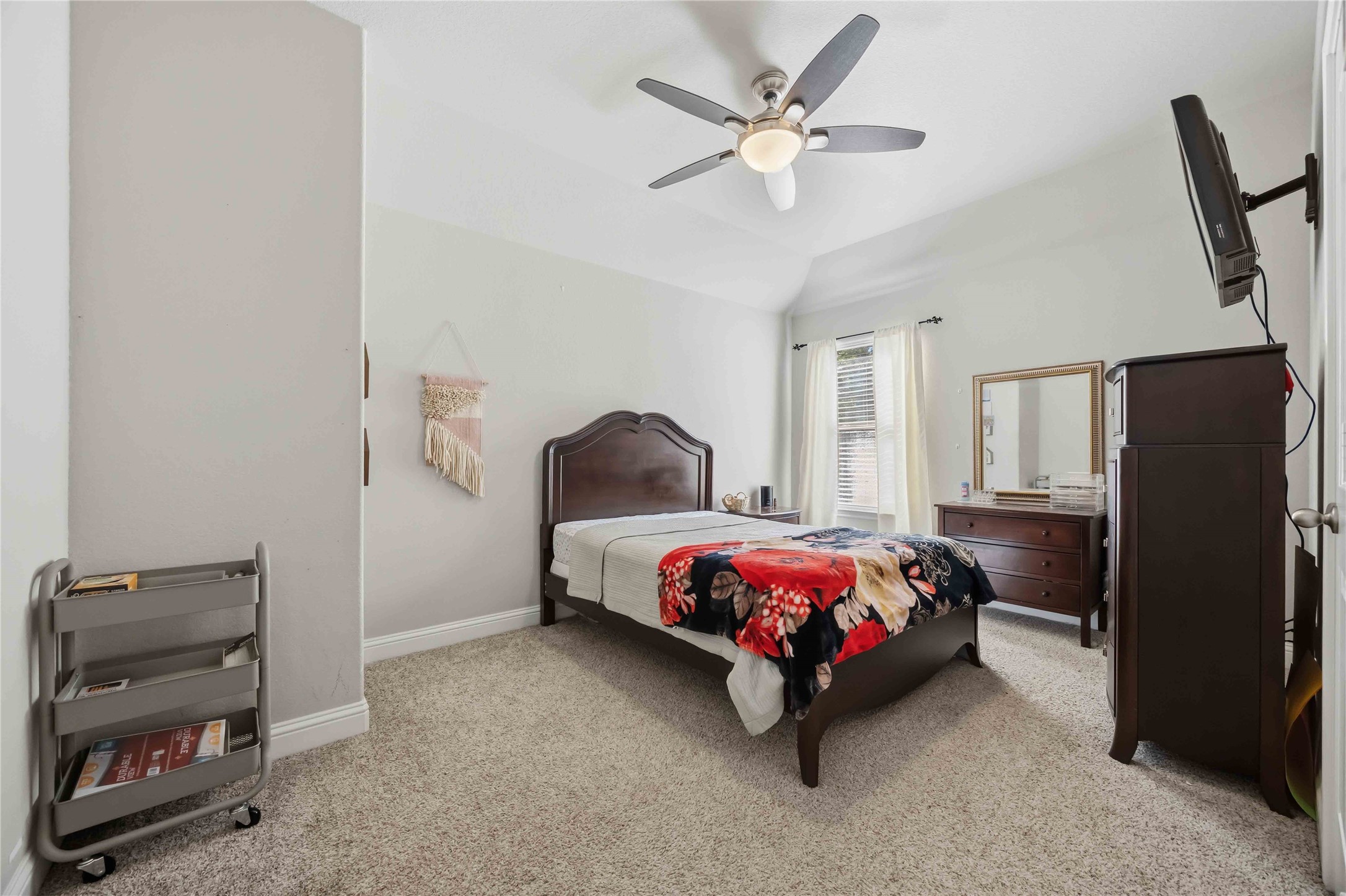 Plush carpet and a ceiling fan make this generously sized bedroom a comfortable retreat.