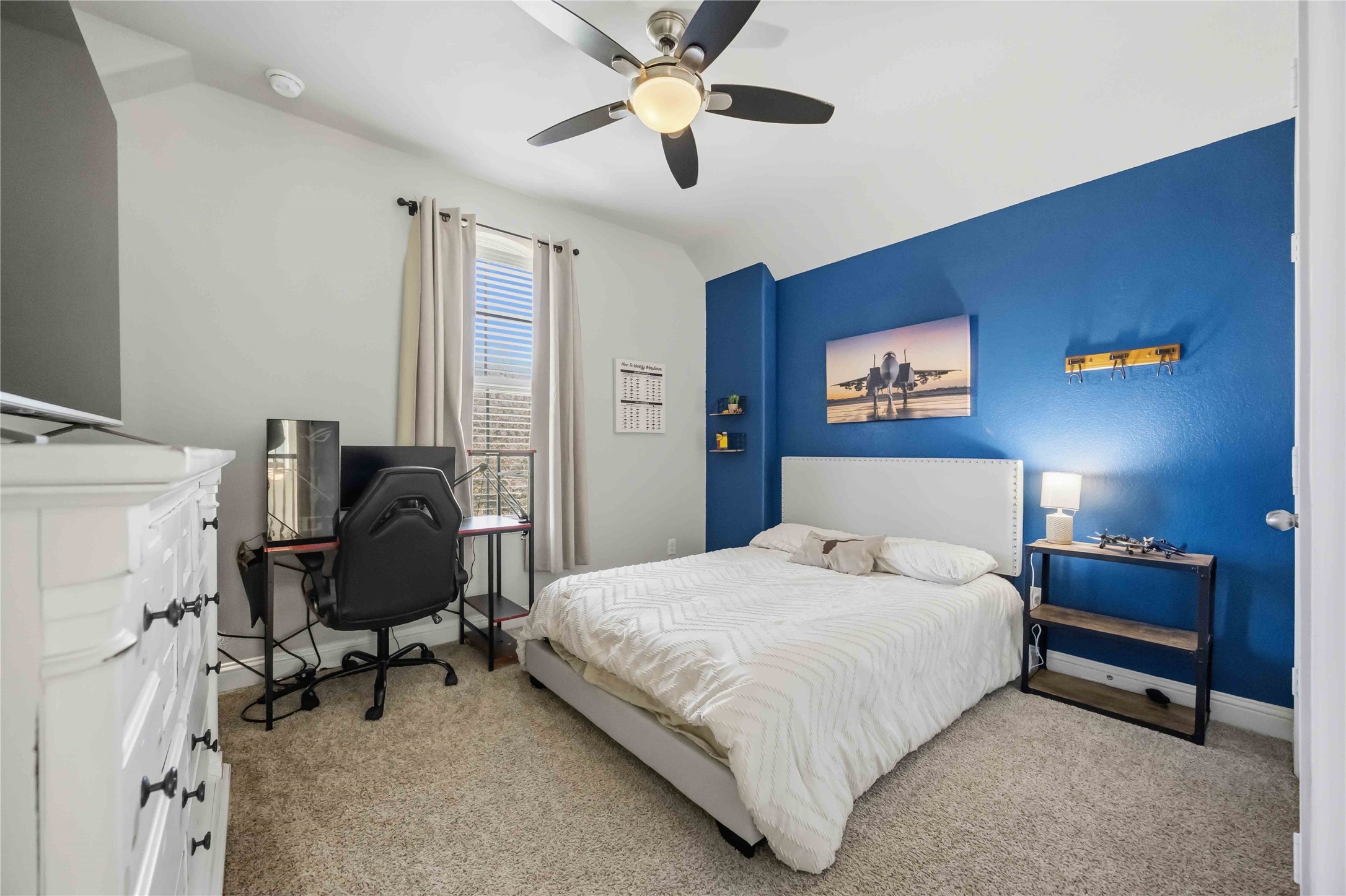Upstairs, a bright bedroom with a blue accent wall has room for a bed and a workspace.