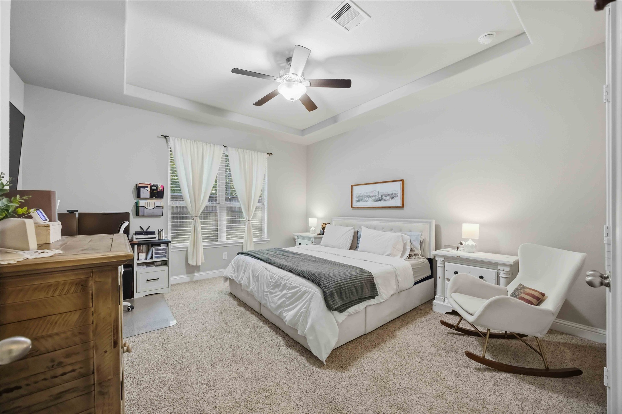 Retreat to the main-floor primary suite, where a tray ceiling adds a sense of calm and space.