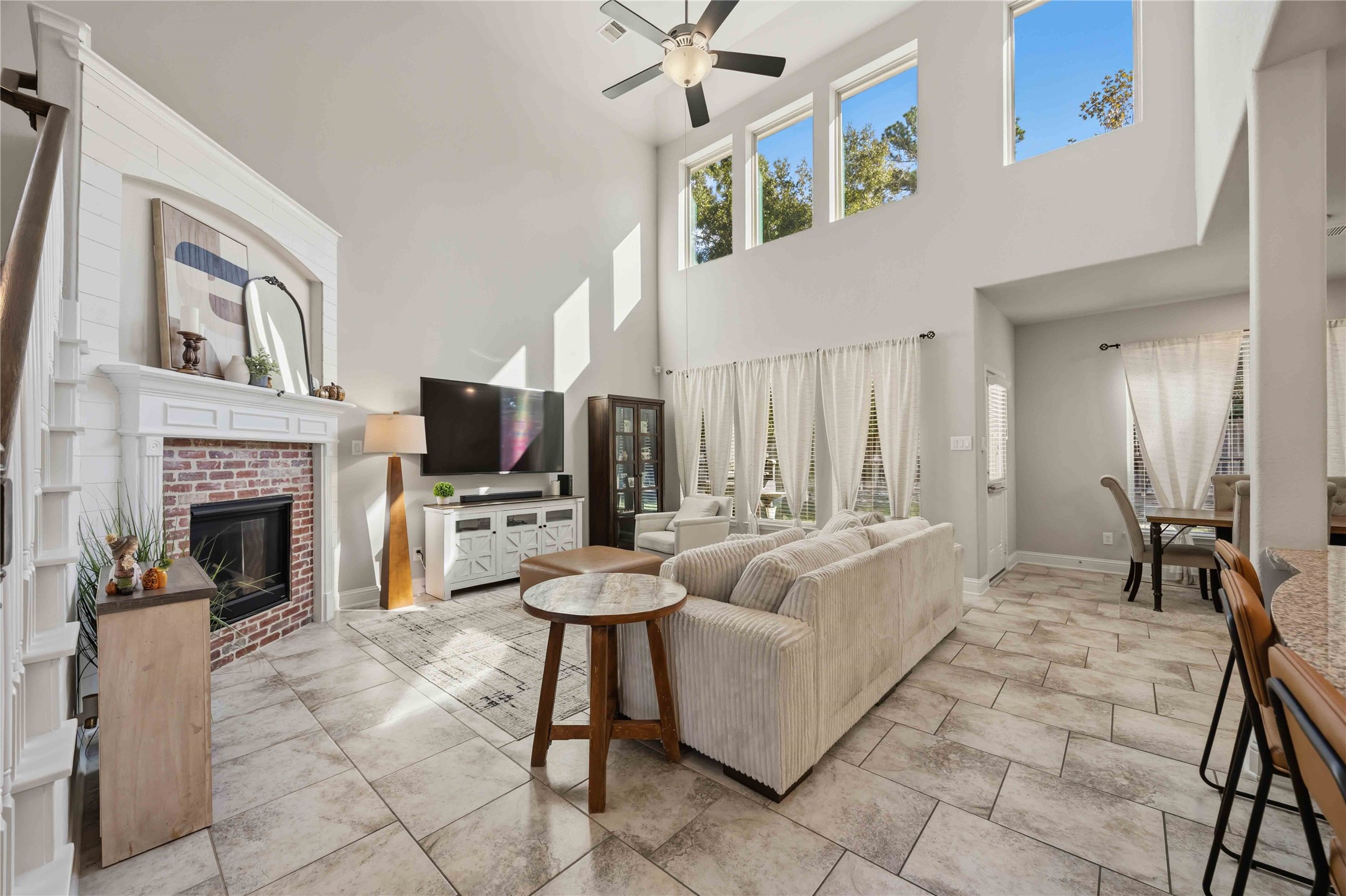 Walls of windows pour light into the two-story living room, anchored by a cozy fireplace.