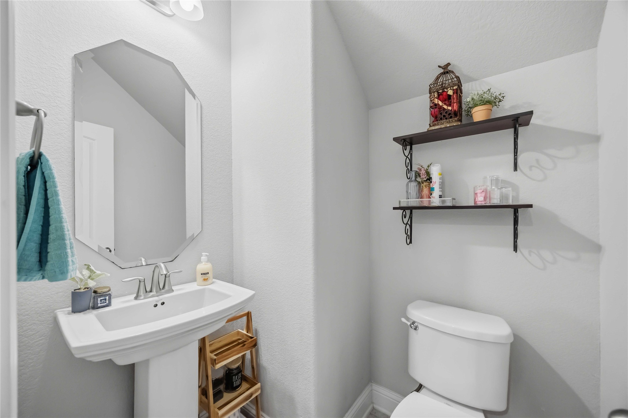 The powder bath is a charming spot for guests, with a pedestal sink and floating shelves.