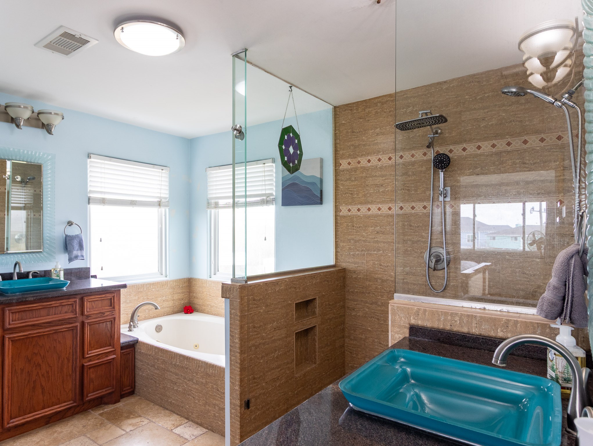 Primary ensuite bathroom with dual shower heads. Glass vessel sinks and jetted whirpool spa tub.