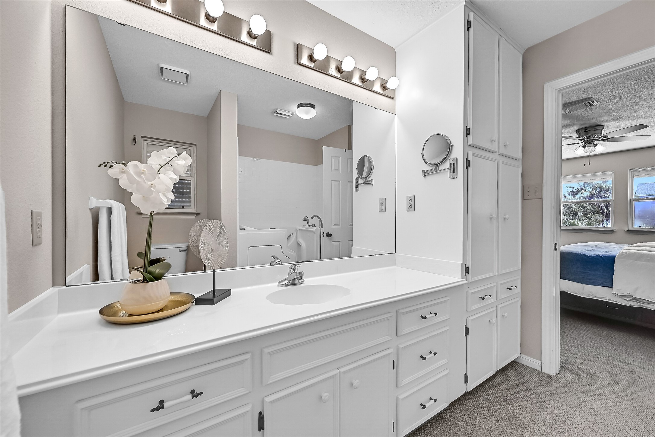 The ensuite bath features a large vanity with extensive storage, built-in cabinetry, and plenty of counter space. Neutral finishes and a functional layout provide a clean, comfortable space to begin and end each day.