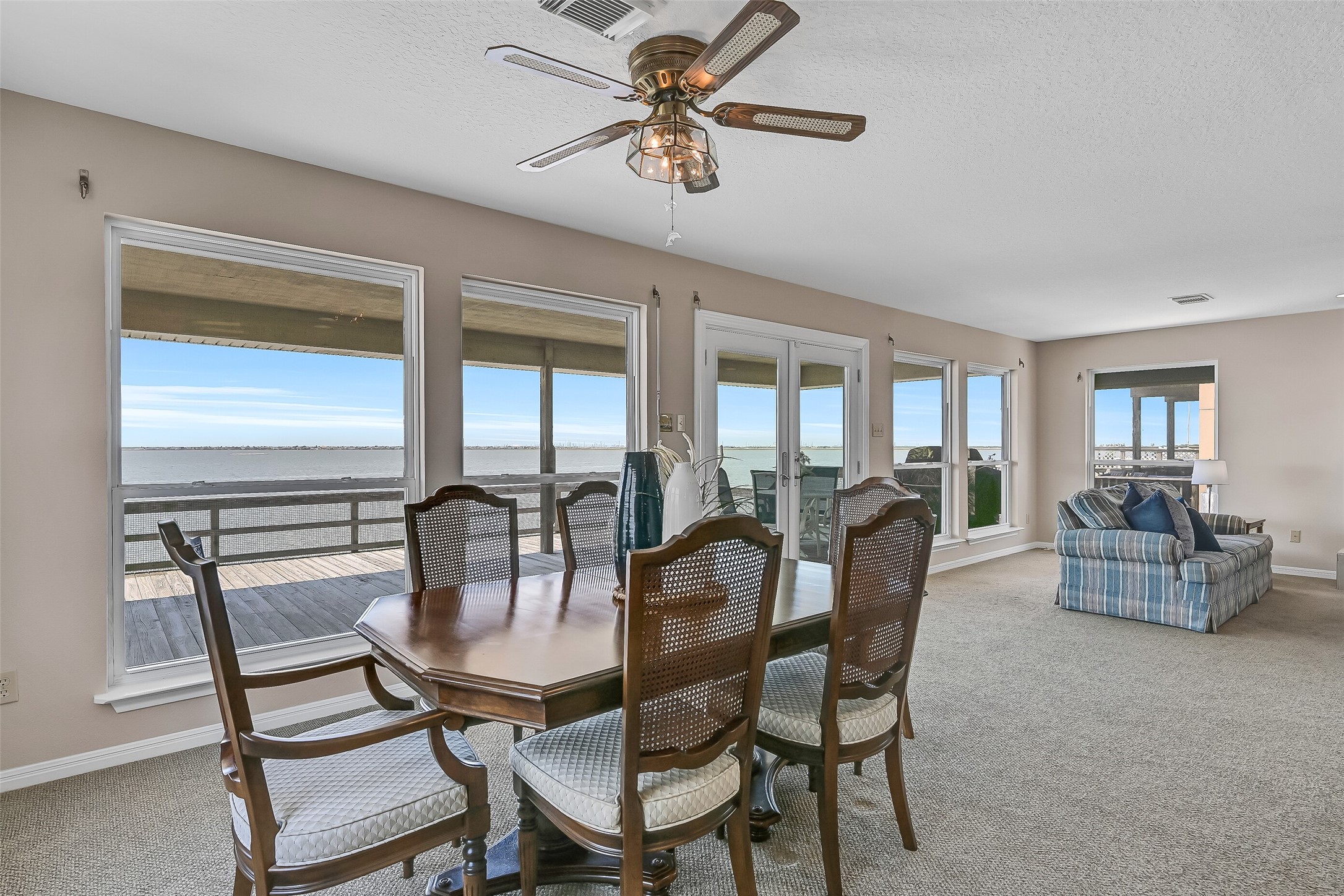 Imagine enjoying every meal with a waterfront backdrop. Positioned alongside a wall of windows and French doors, the dining area offers front-row views of the bay and convenient access to the deck for seamless indoor-outdoor entertaining.