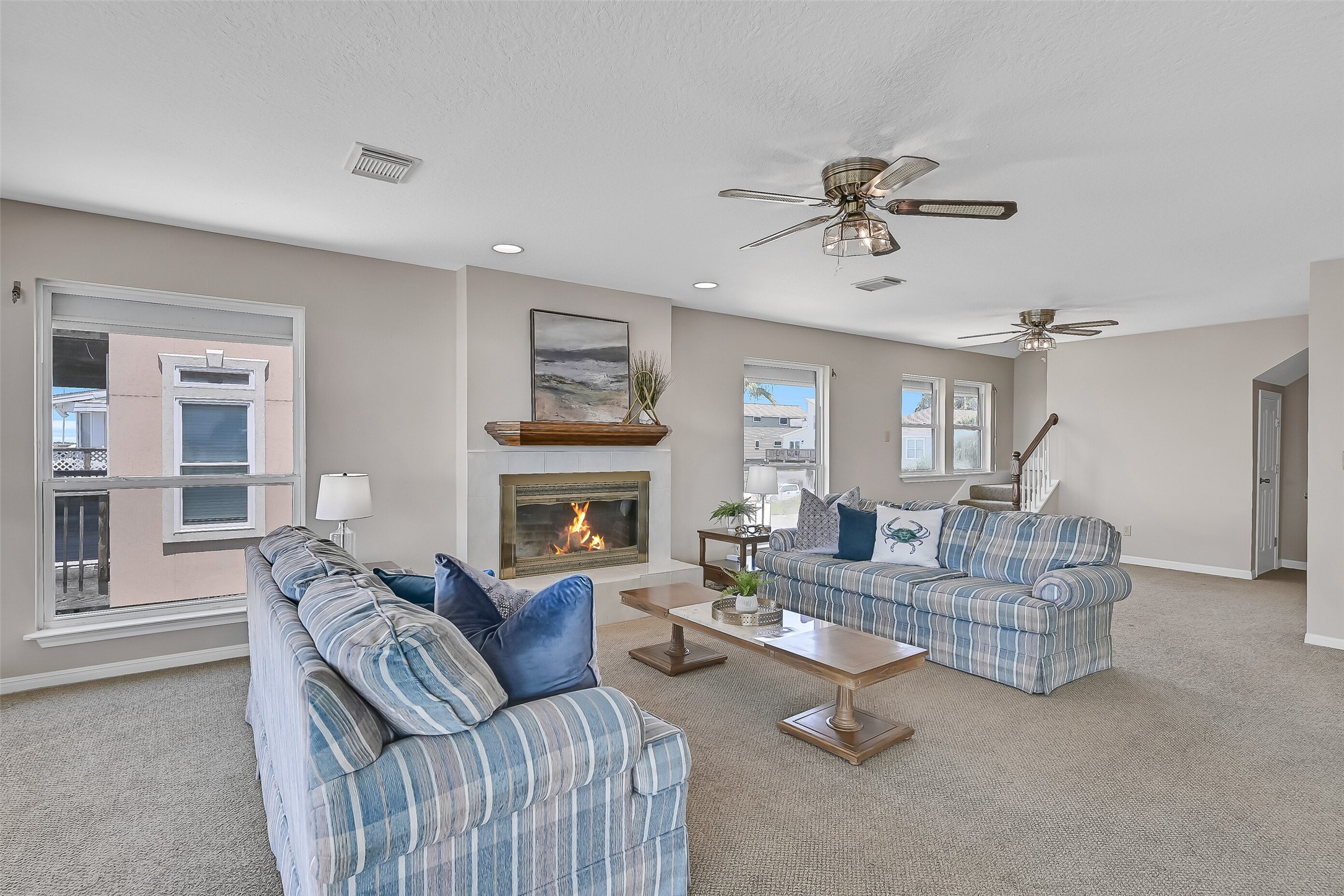 Gather with family and friends in this spacious living area where bay views remain the focal point. Berber carpet, ceiling fans, recessed lighting, and a classic wood mantel create a warm and inviting space to relax after a day on the water.