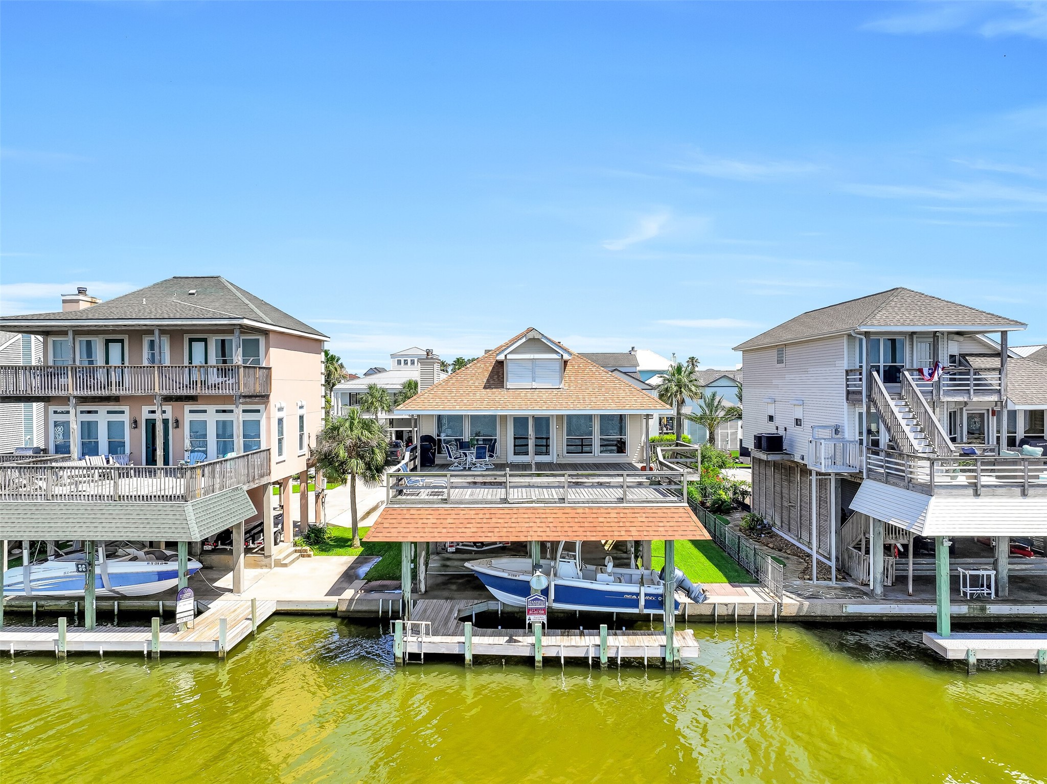 The rear elevation showcases everything that makes coastal living special, including a large entertaining deck, covered boat lift, private dock, and expansive water frontage. Whether you're heading out on the boat or relaxing with friends, the bay is always the centerpiece of the experience.