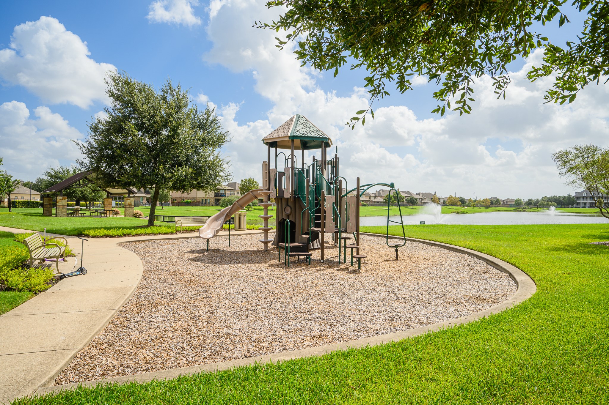 Nestled in a charming neighborhood, this inviting playground features modern equipment, lush greenery, and a scenic pond view, creating the perfect setting for family fun and relaxation.