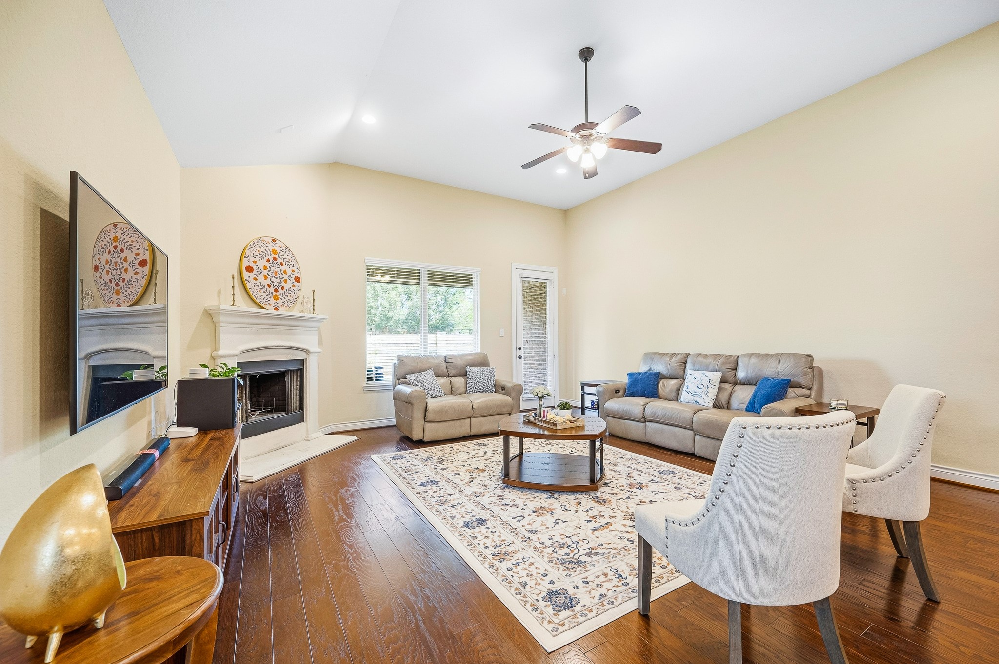 Spacious living room combines relaxation and entertainment with high ceilings, a cozy fireplace, and elegant hardwood floors.