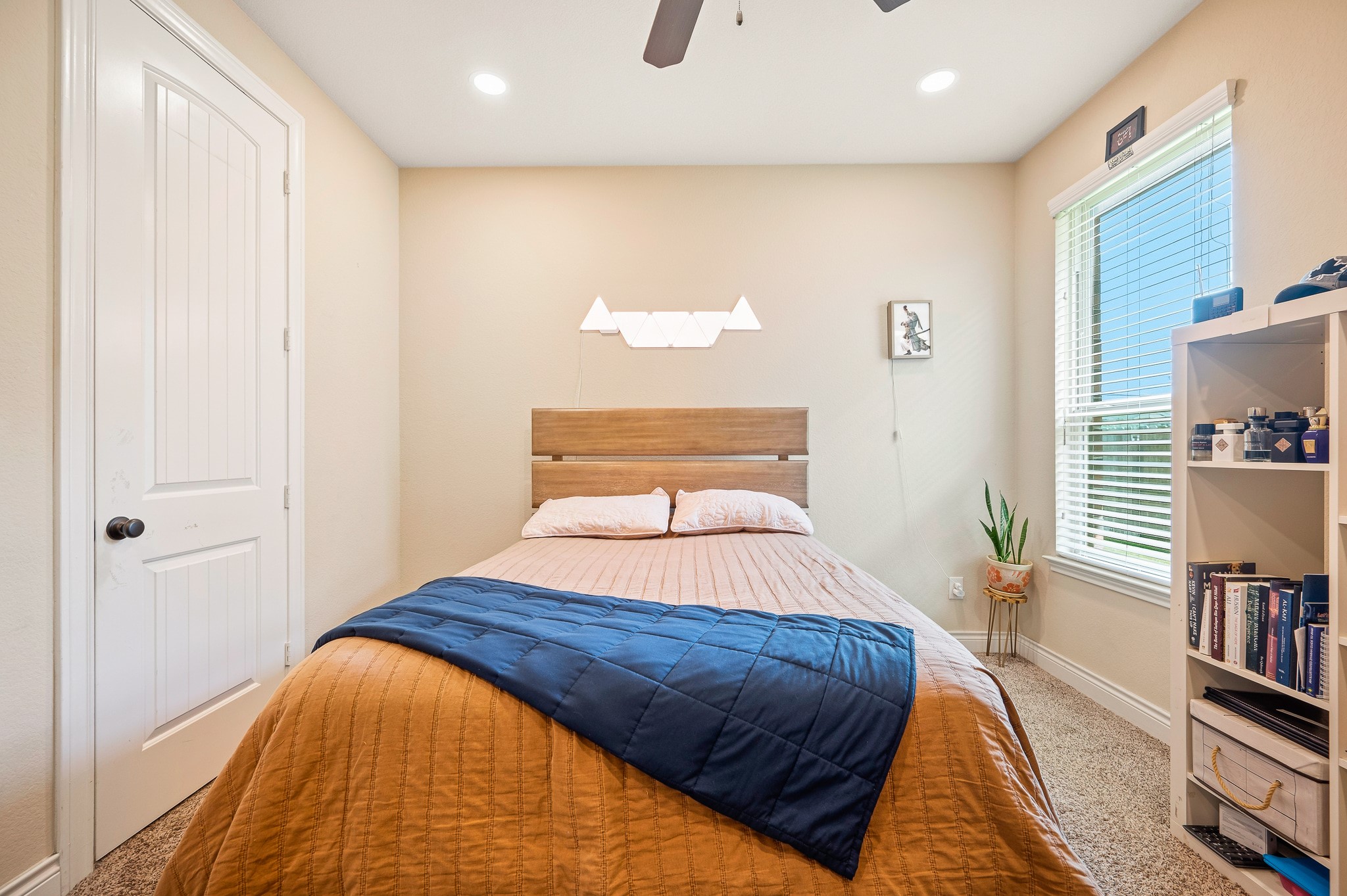A cozy bedroom exuding comfort and style, featuring a chic wooden headboard, soft lighting, and a window that bathes the space in inviting natural light.
