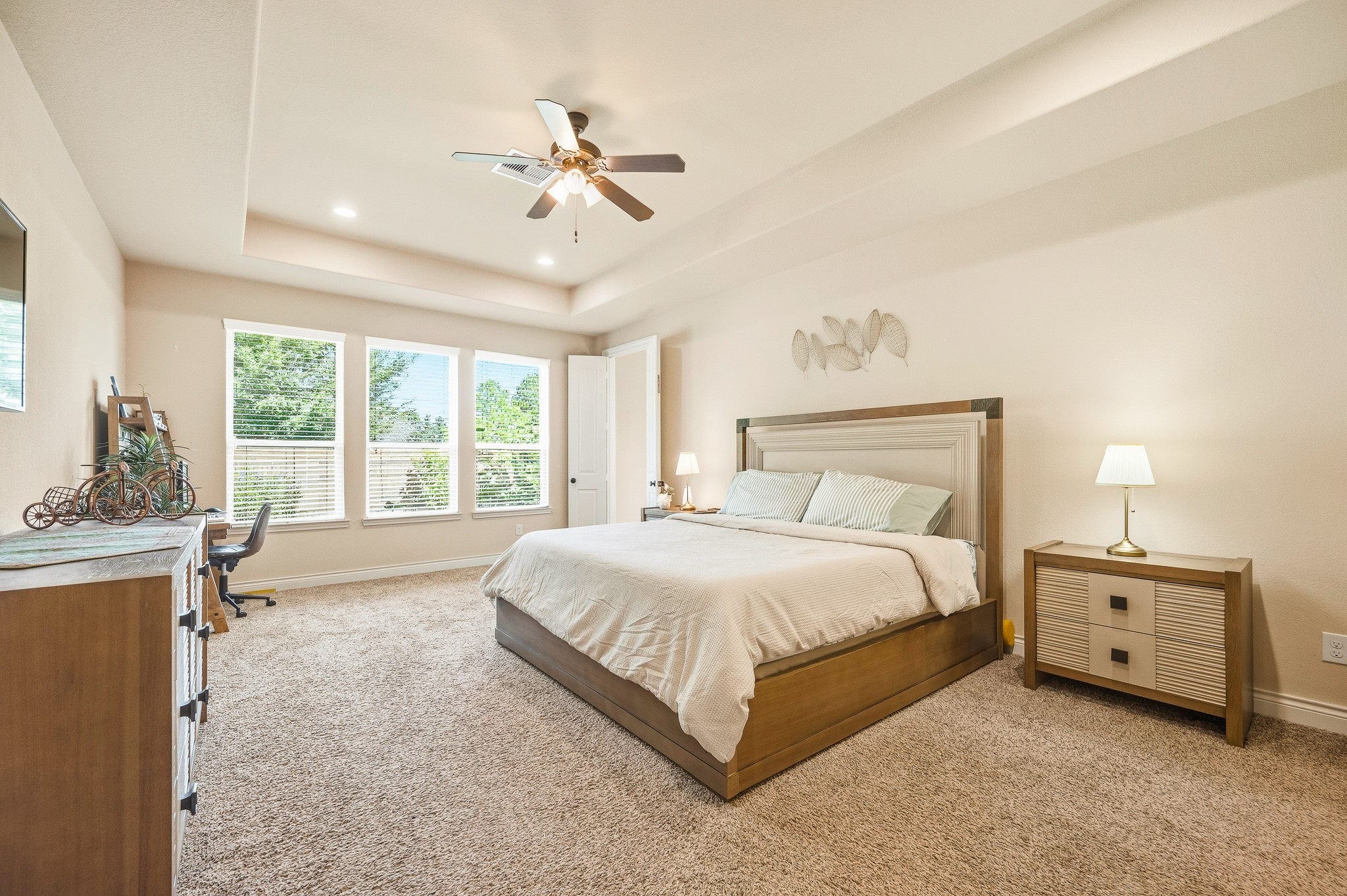 A spacious and inviting bedroom, illuminated by large windows that flood the room with natural light, is complemented by plush carpeting for a cozy and relaxing atmosphere.