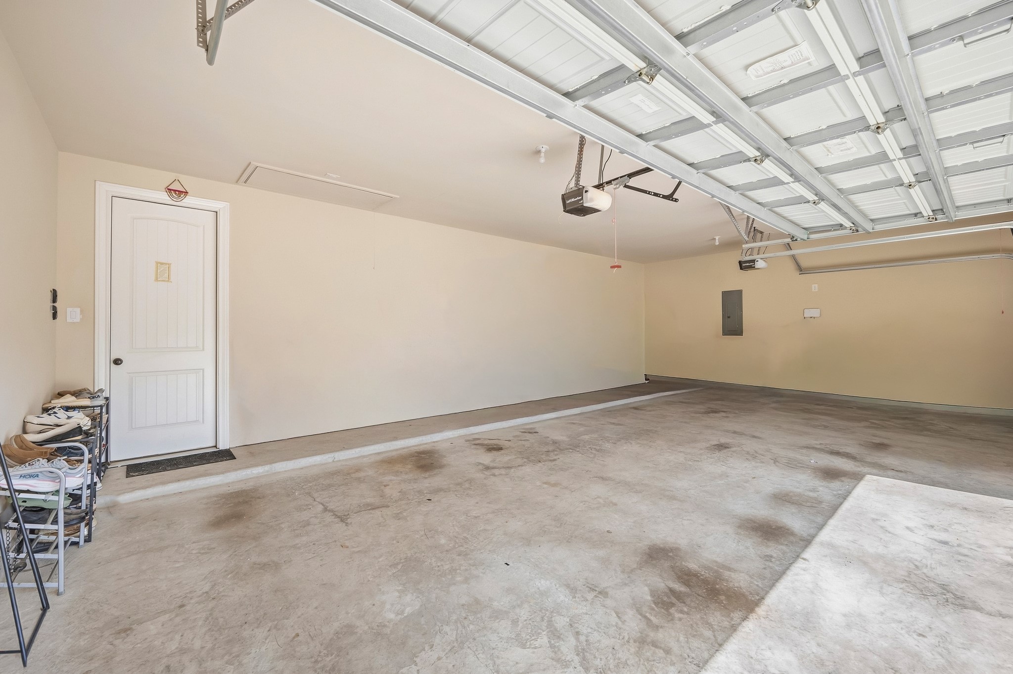 Spacious three-car garage with ample floor space, overhead storage, and interior access through a side door, making it perfect for all your storage and parking needs.