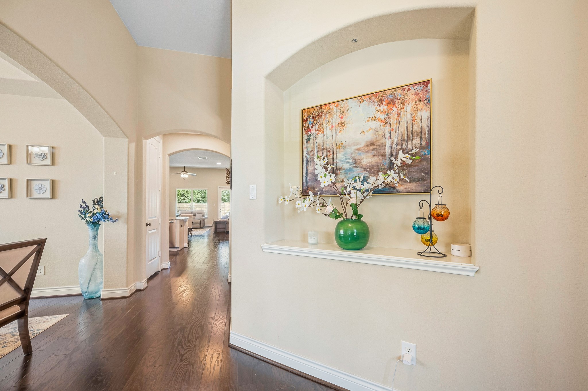 Discover a charming entryway with elegant archways, warm wood flooring, and tasteful decor that seamlessly leads to a bright and welcoming living area.