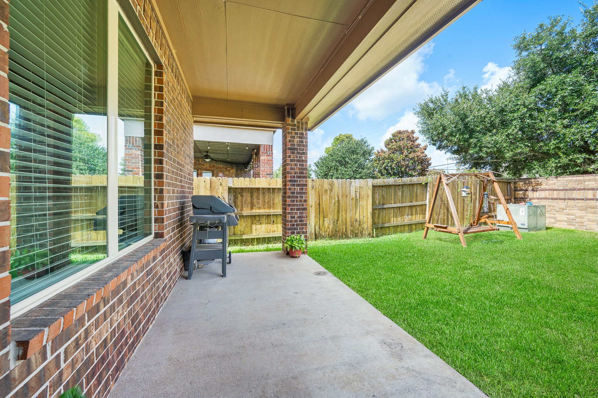 Experience serene outdoor living and entertaining on a charming covered patio, seamlessly overlooking a lush, fenced backyard.