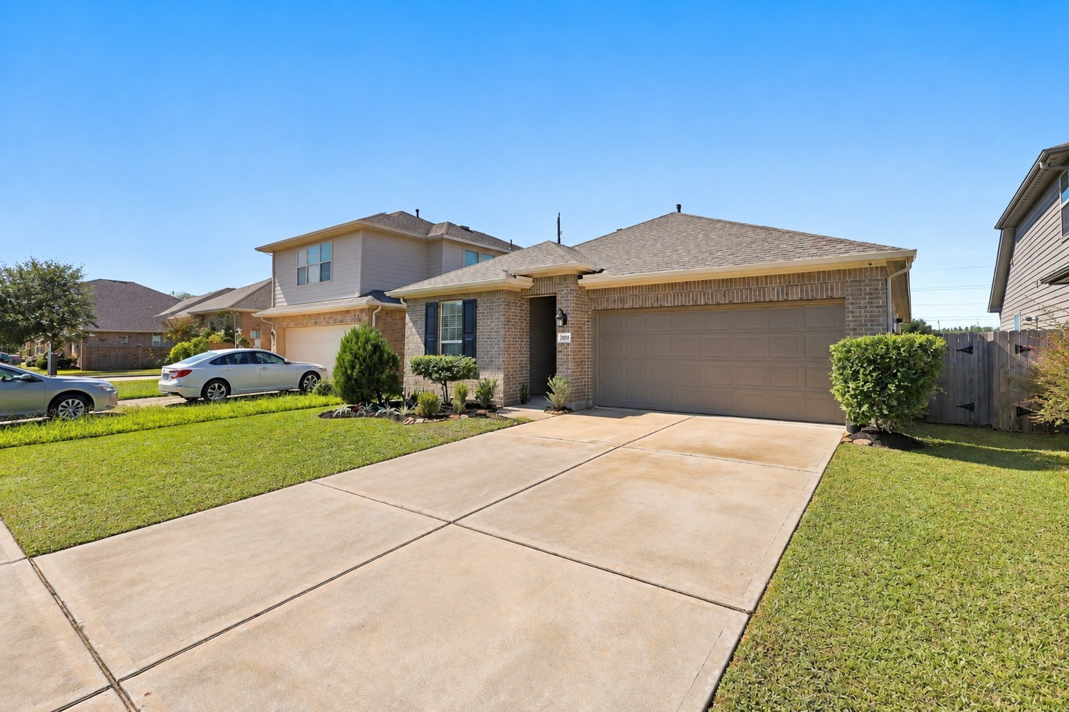 Attractive brick exterior, mature shade tree, and spacious driveway along a cul-de-sac street.