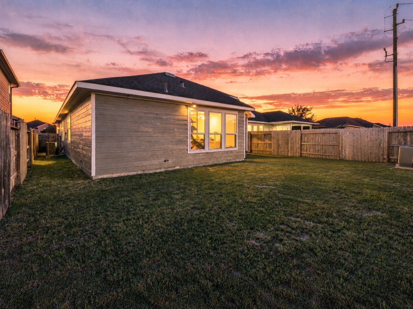 Evening view highlights the home's rear exterior, illuminated windows, and spacious outdoor setting.