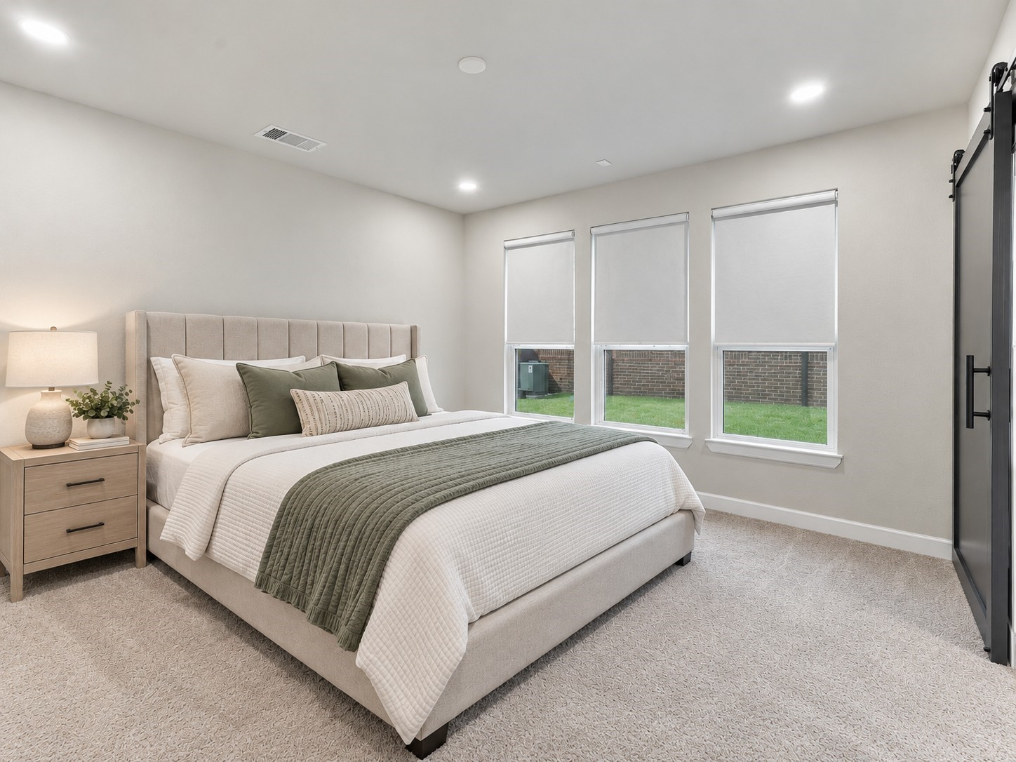 Spacious primary bedroom with soft carpeting, neutral finishes, and multiple windows overlooking the yard.**Virtually staged