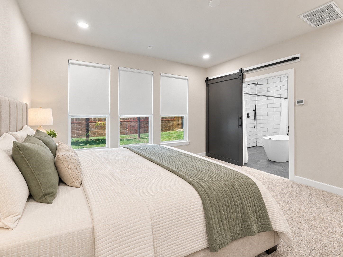 Private primary suite with direct access to the ensuite bathroom through a sliding barn door.**Virtually staged