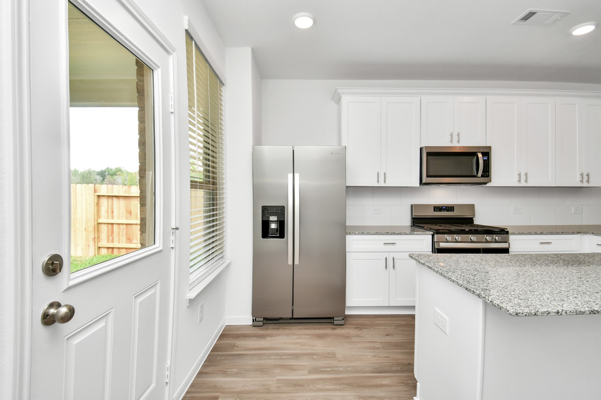 The kitchen blends indoor and outdoor living, with access to the back patio in a perfect blend of functionality, style, and the beauty of nature, creating a welcoming and versatile space.