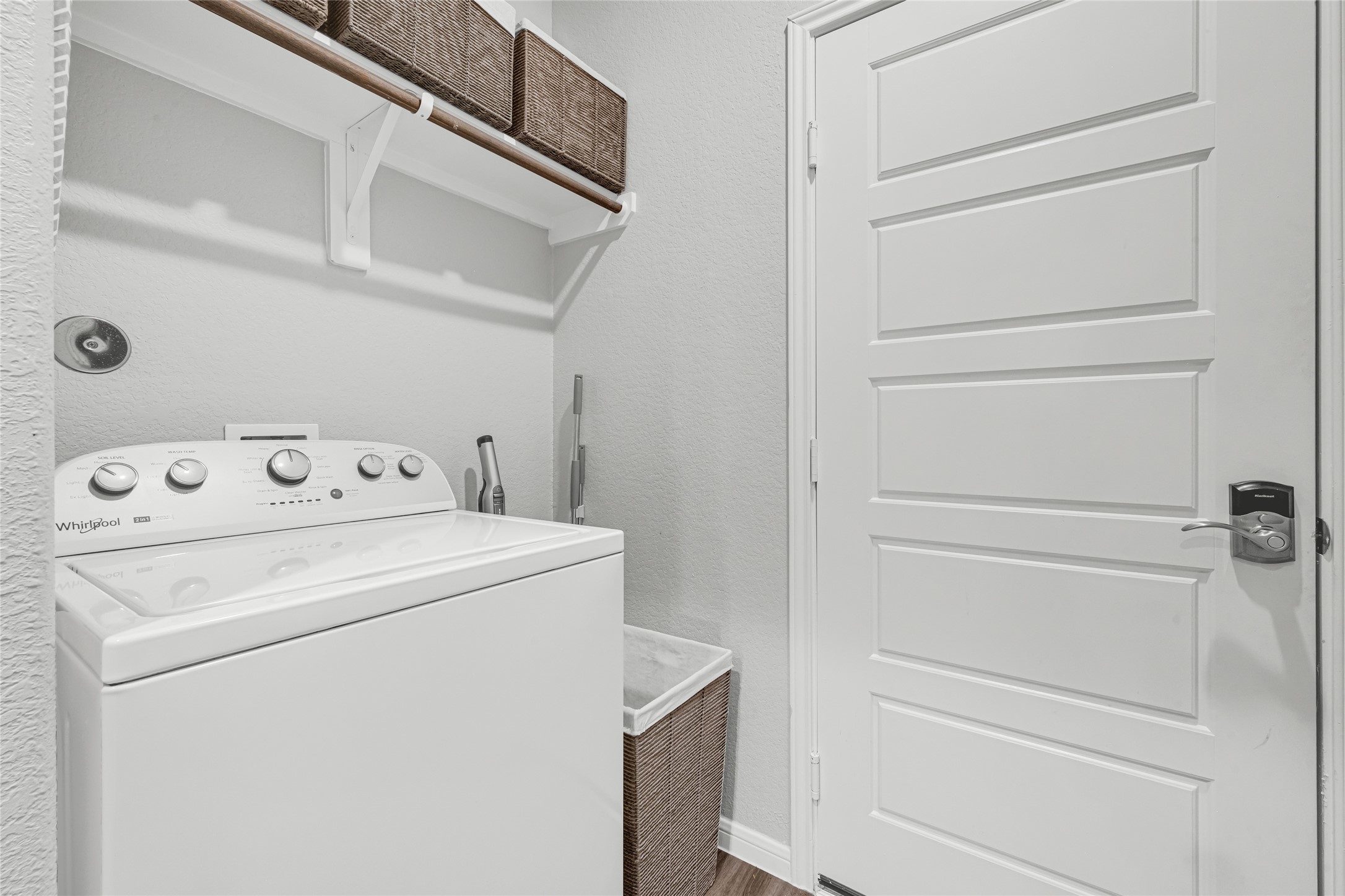 Discover a functional and tidy laundry room with a hanging rod, overhead storage, and ample space for essentials, perfect for streamlined household chores.