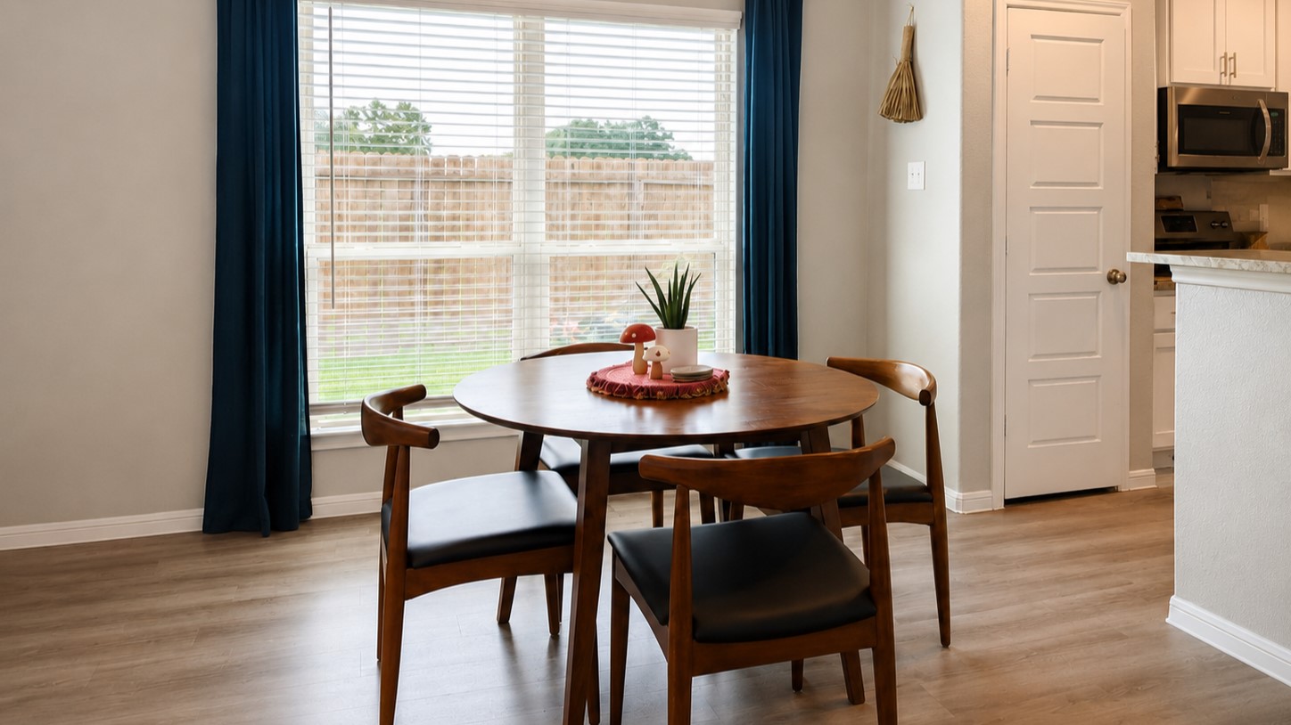 This inviting dining area boasts modern design with sleek vinyl plank flooring, enhanced by large windows that flood the space with natural light.