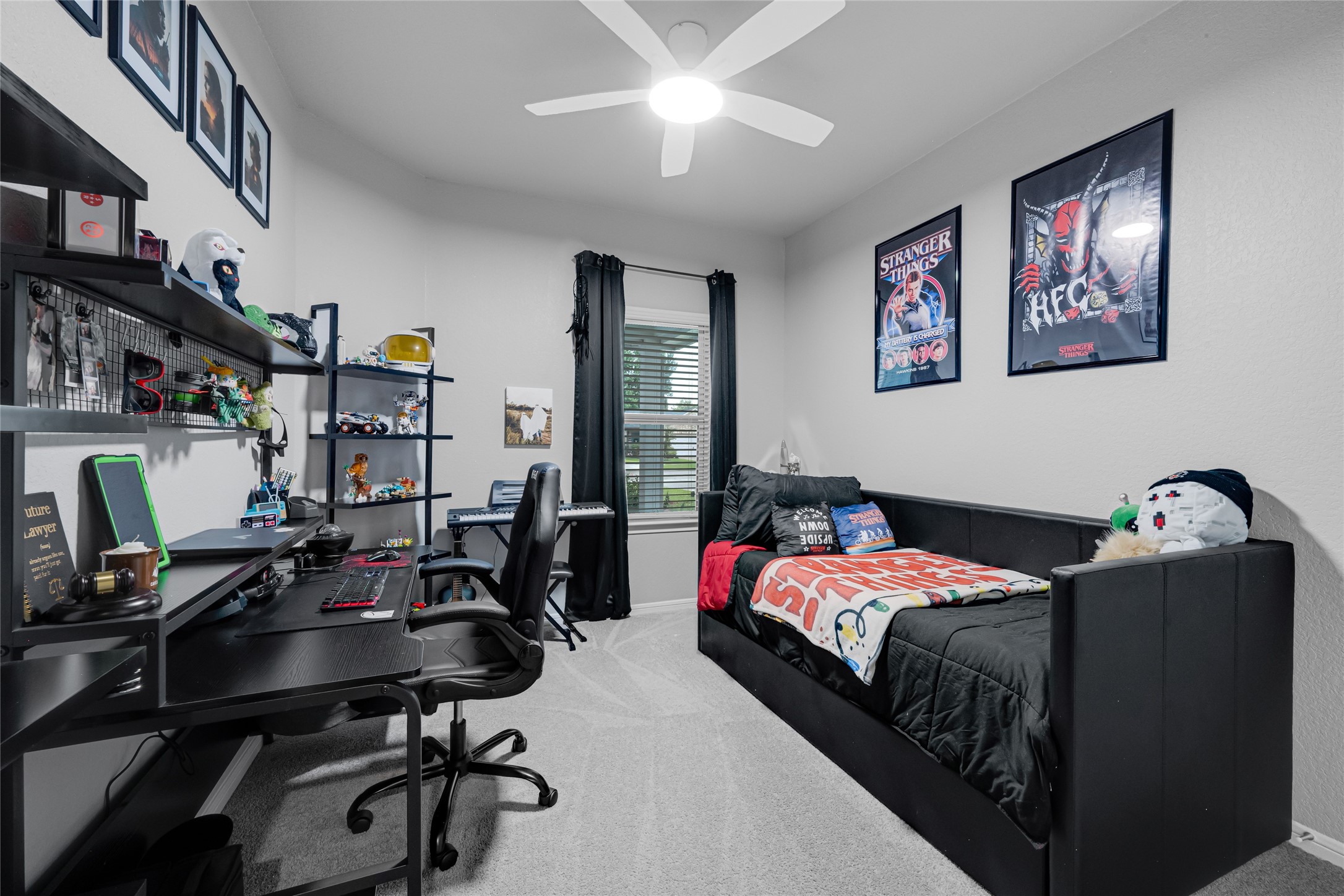 This cozy bedroom features a modern feel. The room is brightened by a ceiling fan and a window with 2 inch faux wood blinds, creating a stylish and functional space.