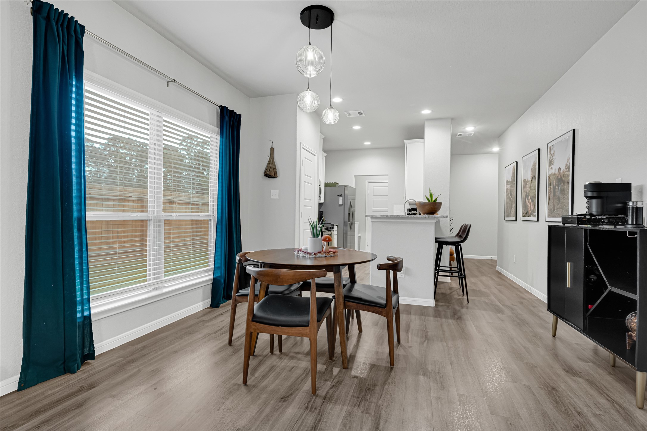 Discover a bright, inviting dining area framed by expansive windows that fill the space with natural light. The open-concept design offers flexibility for everyday living and entertaining, while upgraded designer pendant lighting adds a polished, modern touch.