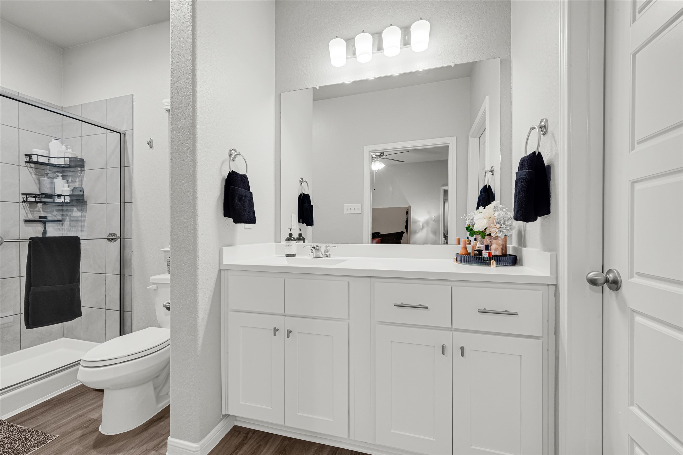 This bathroom features a modern design with a large mirror above a marble vanity countertop sink combo, elegant lighting. Birch cabinets to match kitchen, privacy door lock and satin nickle towel bar and paper holder. The neutral color palette and sleek Moen High Quality fixtures create a clean, inviting atmosphere.