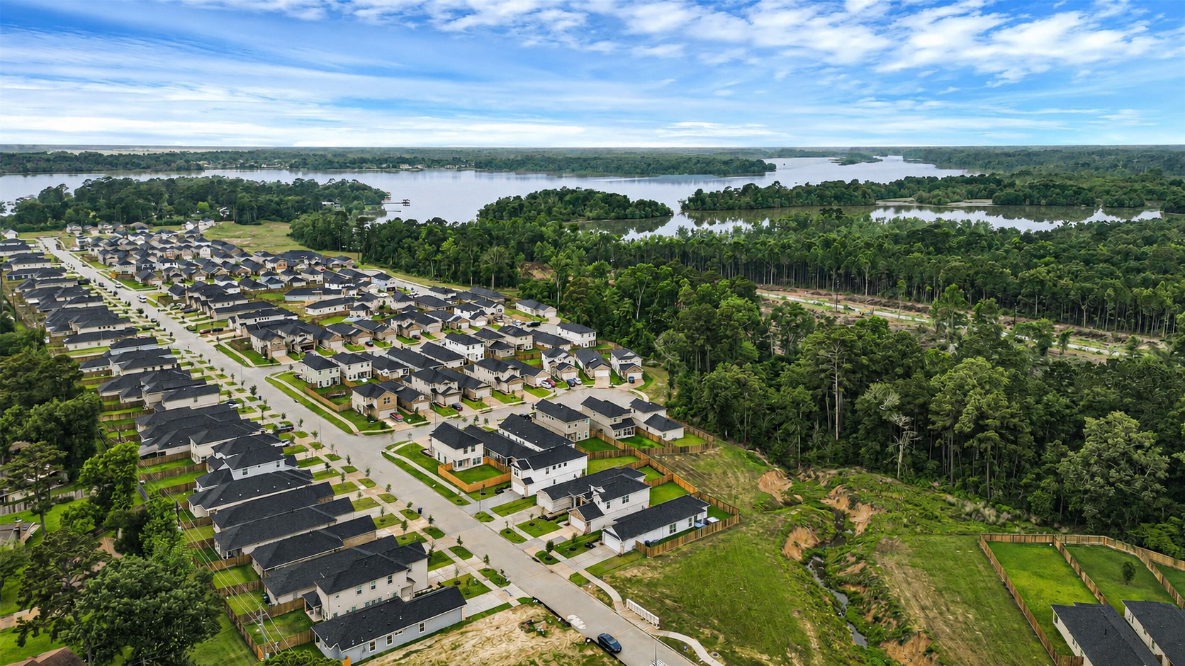 Aerial views tell the whole story  tree-lined streets, modern homes, and dense forest backing the neighborhood, all within walking distance to Lake Houston.